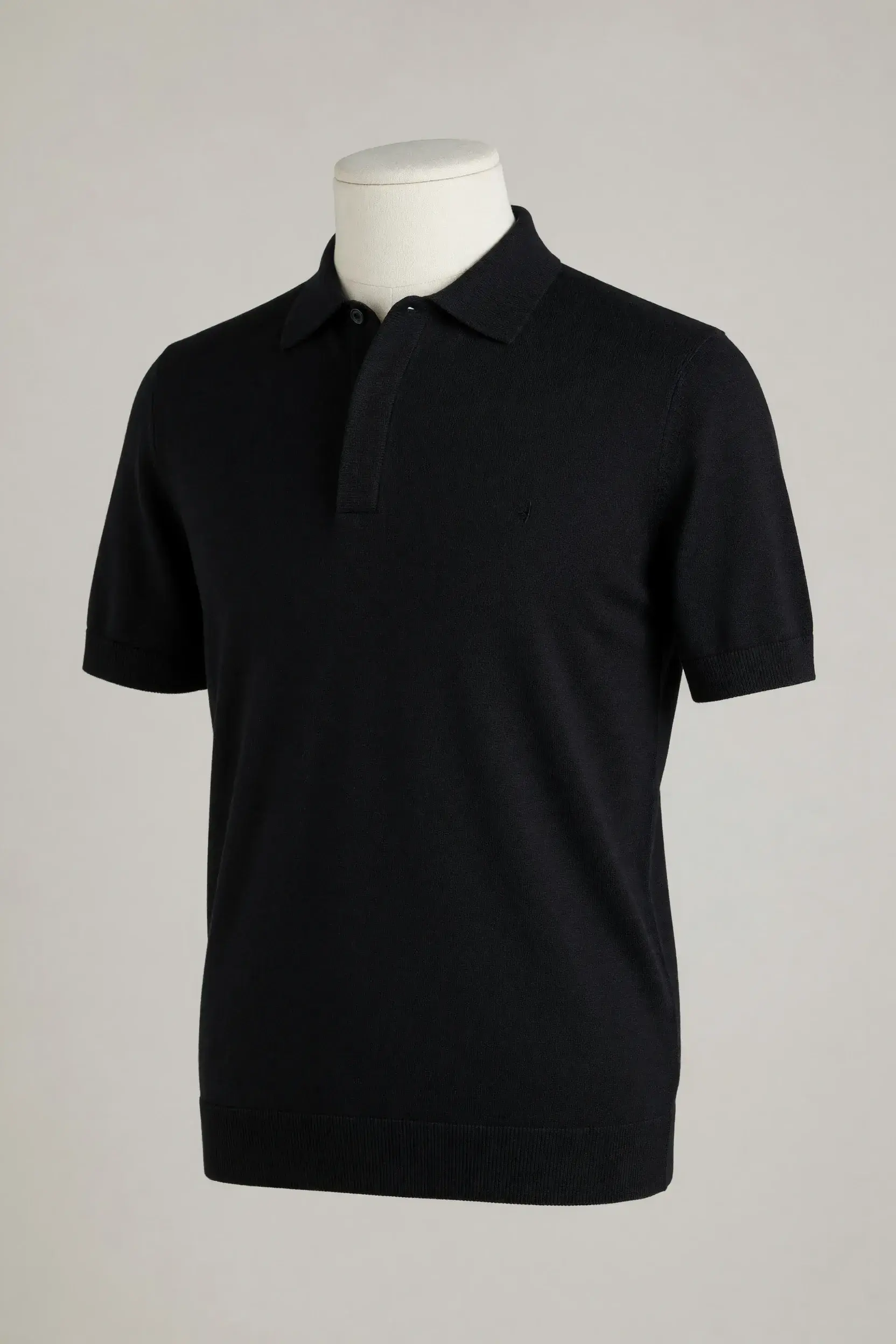 Black hidden-placket short-sleeve knit polo with collar and ribbed hem shown on a mannequin for private-label development