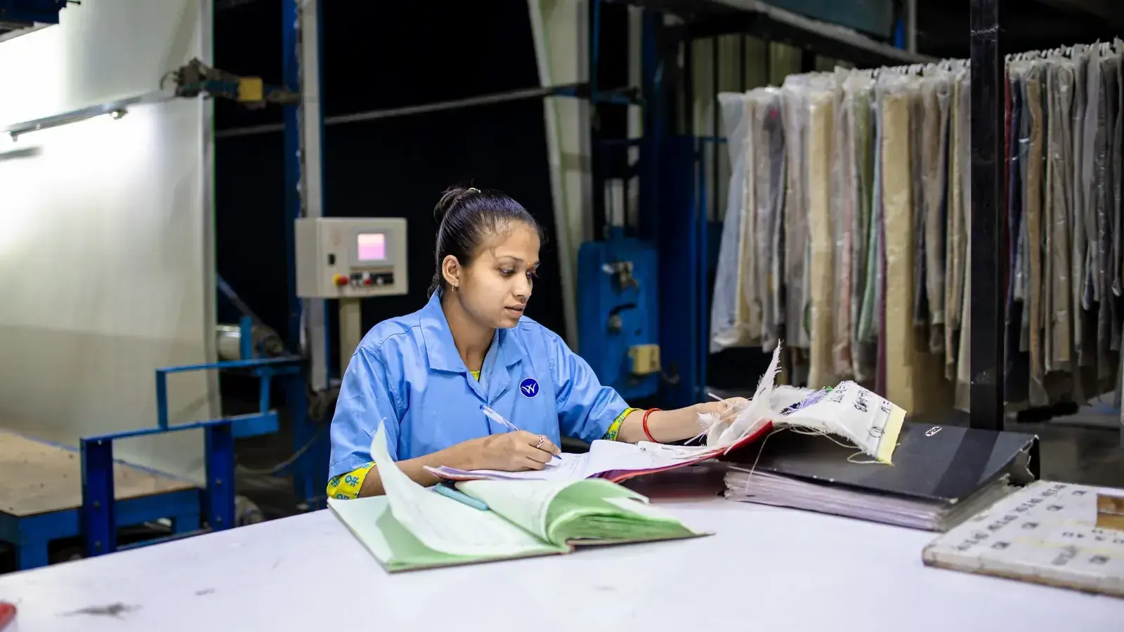 Textile production specialist reviewing documents at a factory workstation