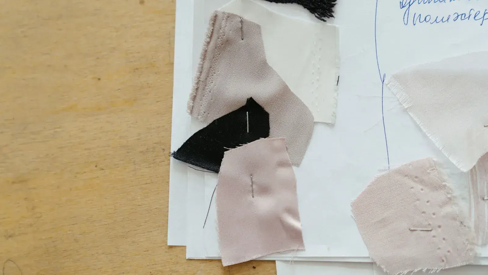 Fabric swatches pinned to an annotated worksheet on a wooden table