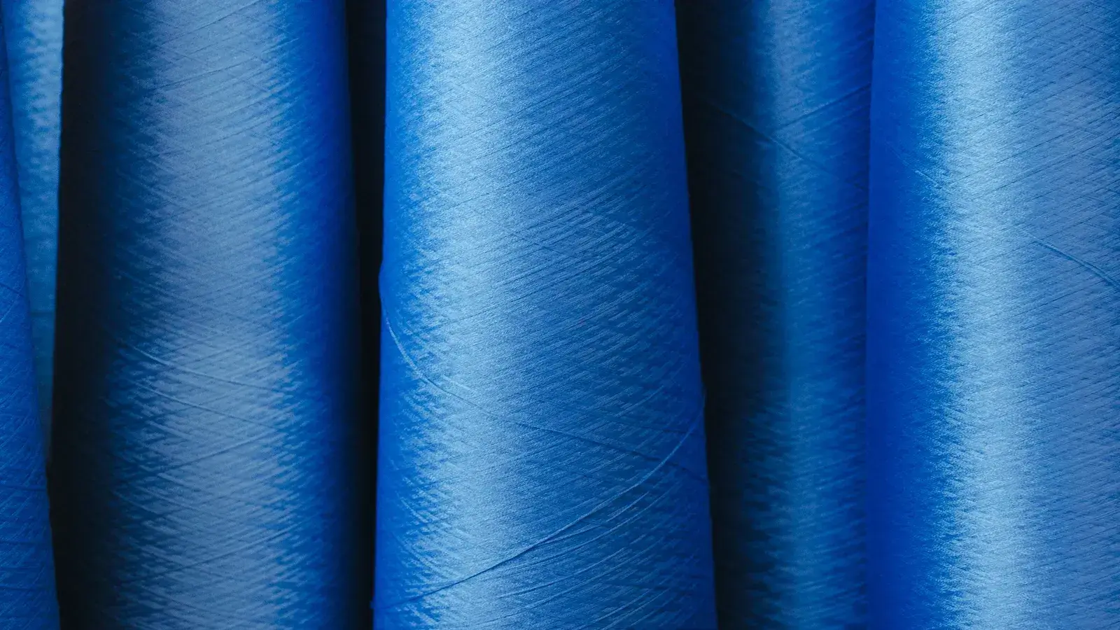 Rows of blue spun yarn packages seen in close-up