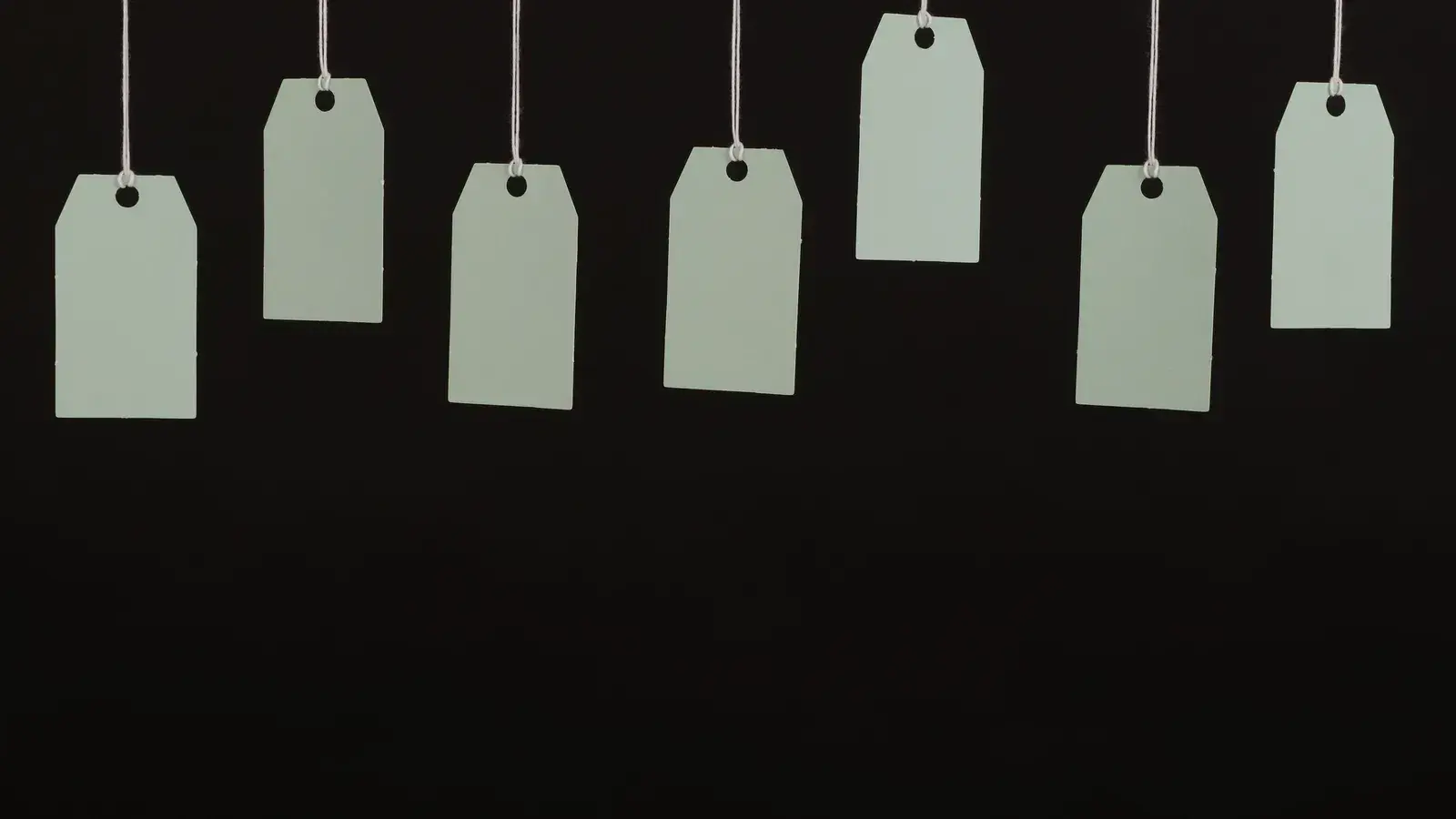 Blank hang tags hanging on strings against a dark background