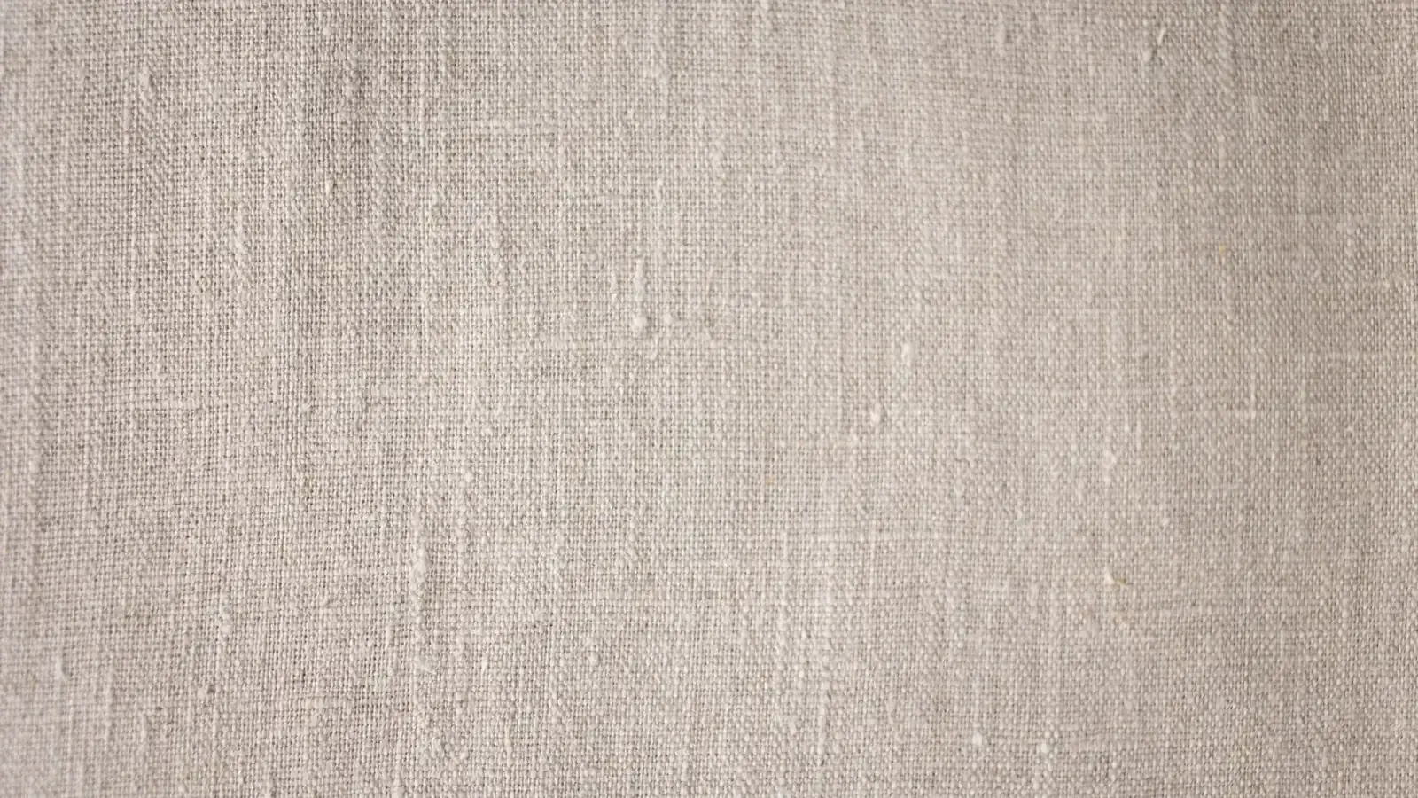 Close-up of natural undyed linen showing visible slub and irregular yarn in the weave