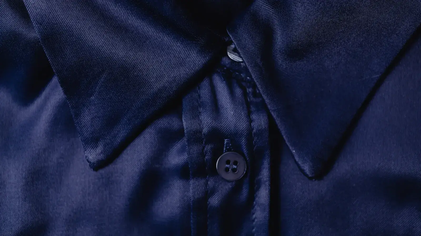 Close-up of a navy collared shirt showing fabric, collar and buttons