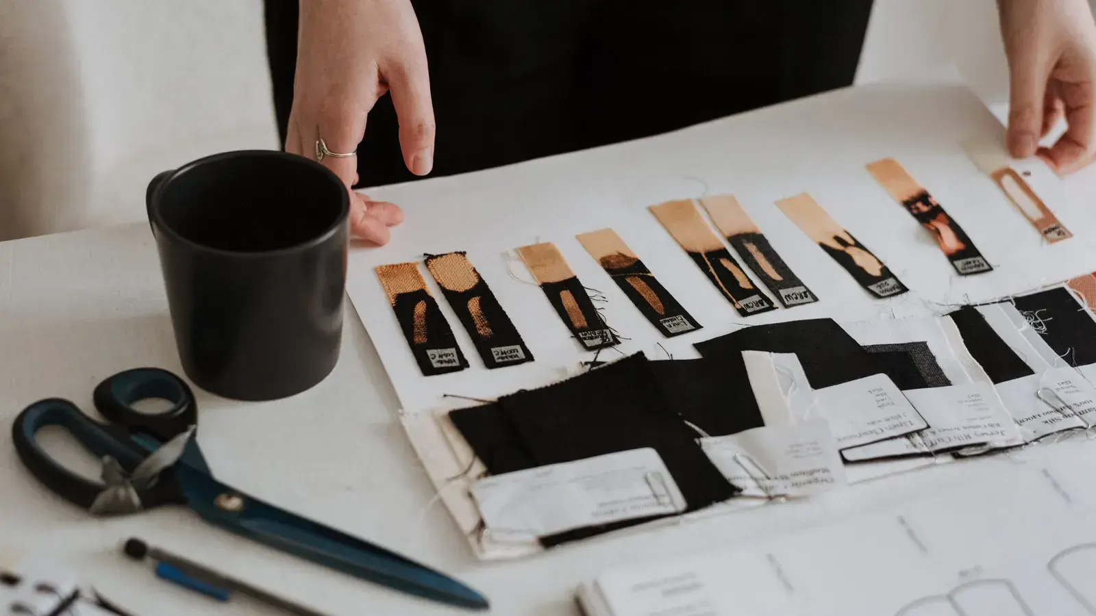 Garment labels, fabric pieces and construction references arranged on a design table