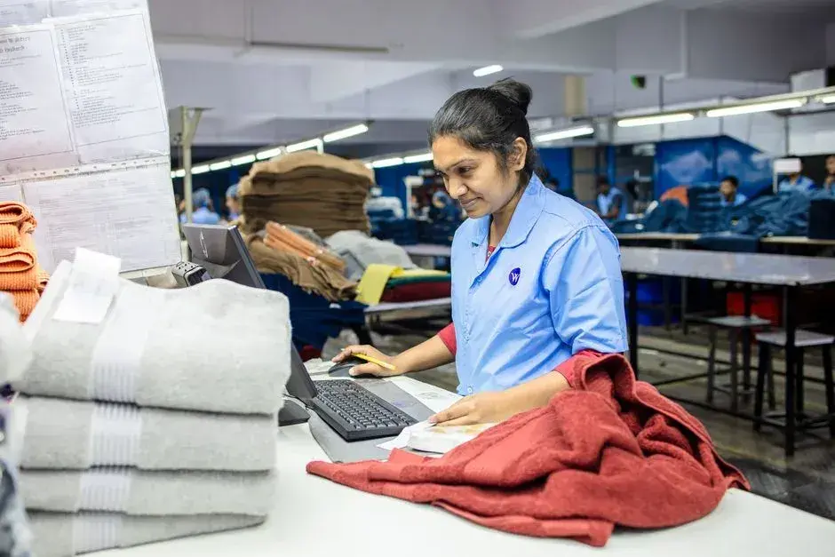 A textile worker checking fabric at an inspection workstation