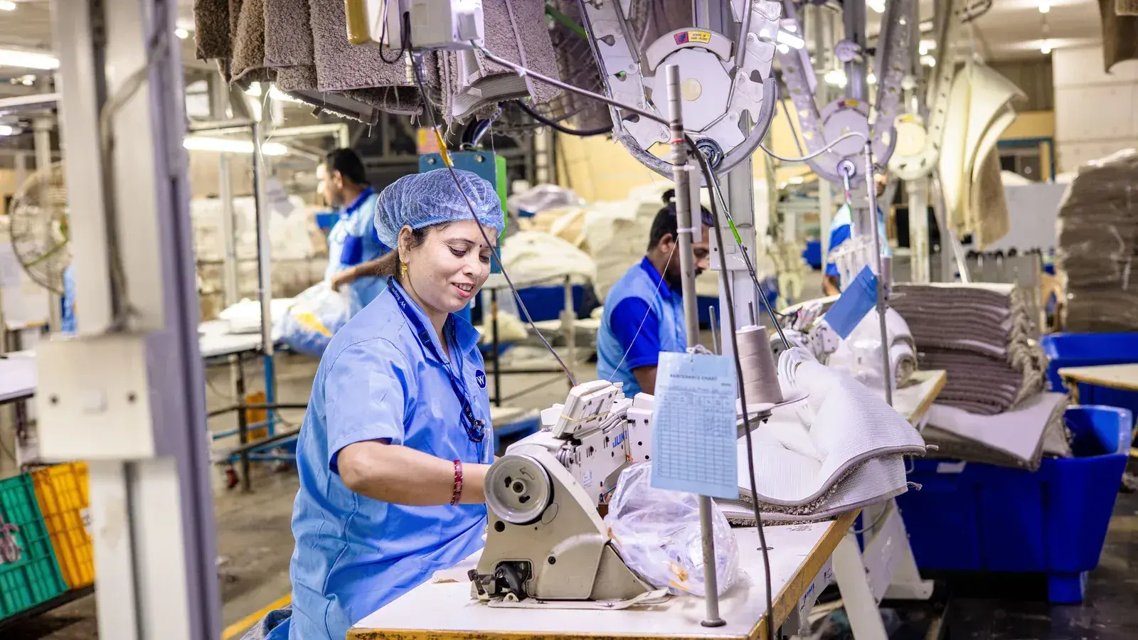 Garment worker operating an overlock machine on a production line