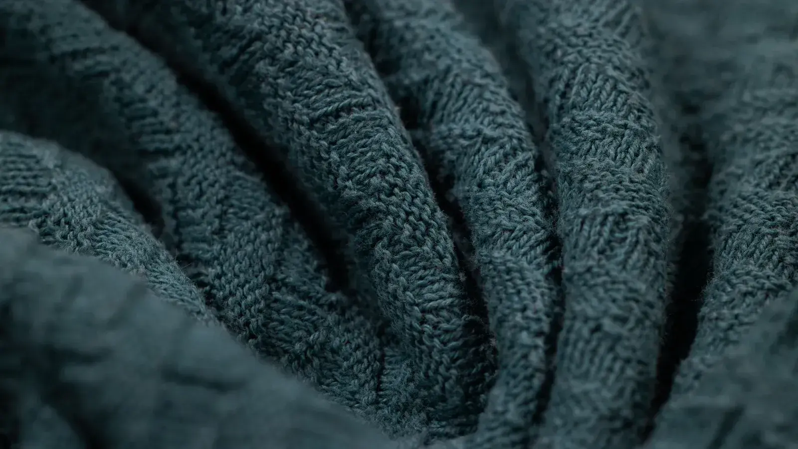 Macro view of a dark knitted fabric showing individual loops and stitch structure
