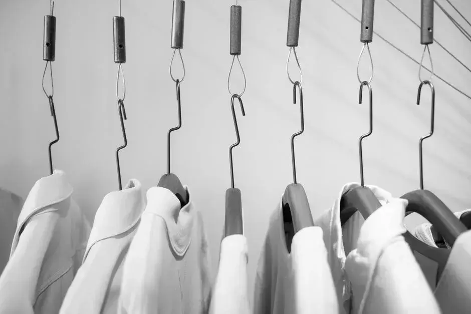 Shirts hanging from ceiling hooks in a store, in black and white