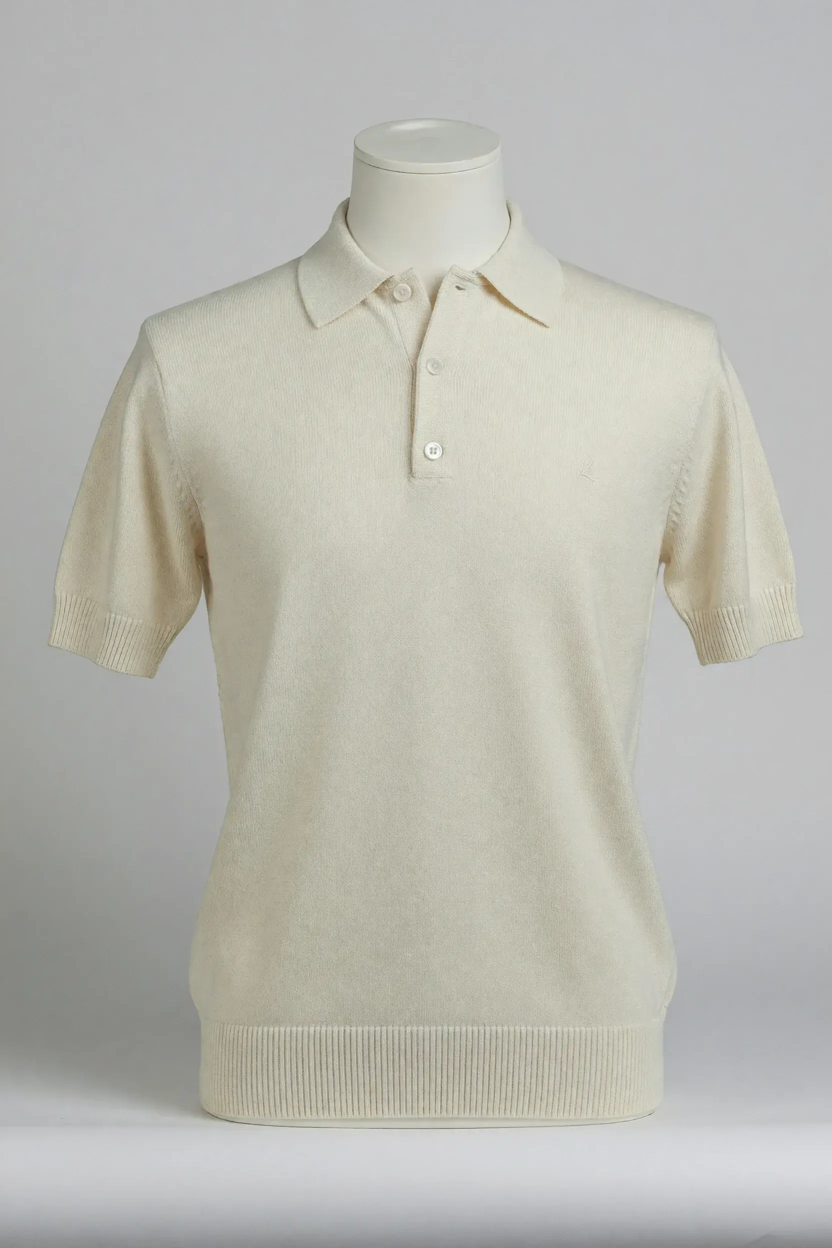 Cream fine-knit three-button short-sleeve polo fitted on a torso mannequin for OEM private-label product development