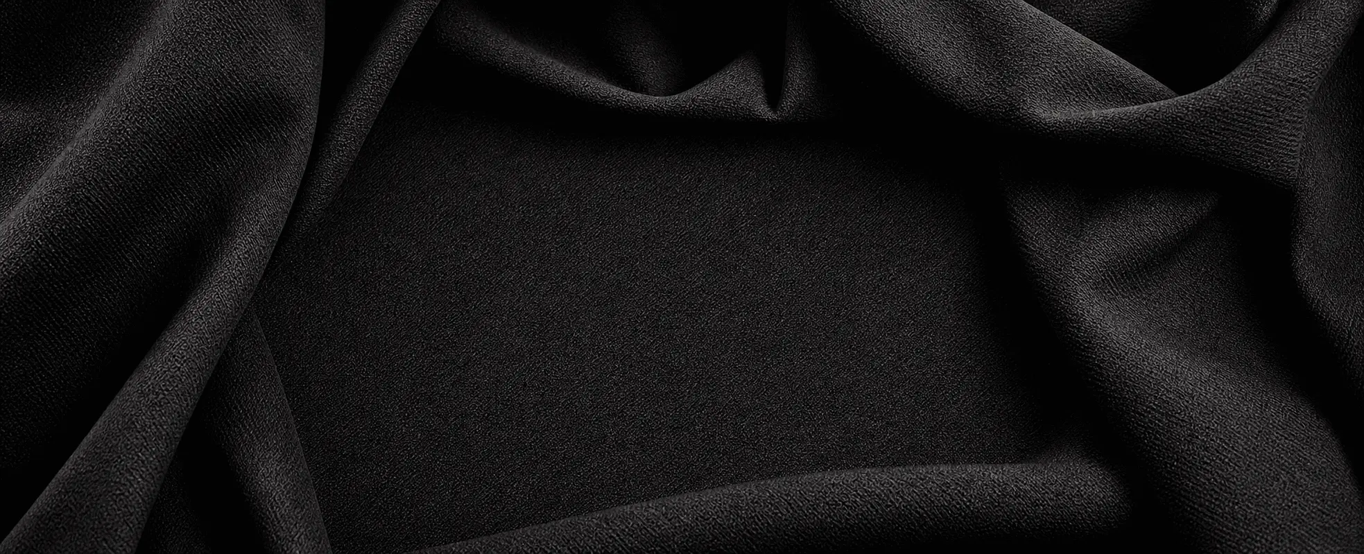 Dark woven fabric folded into a clean hero background for apparel sample development