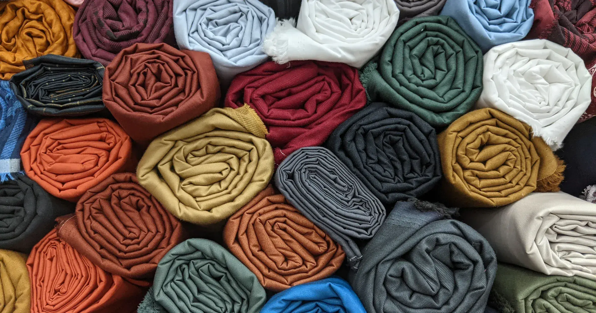 Rolled fabric bolts in solid earth-tone colors stacked for selection