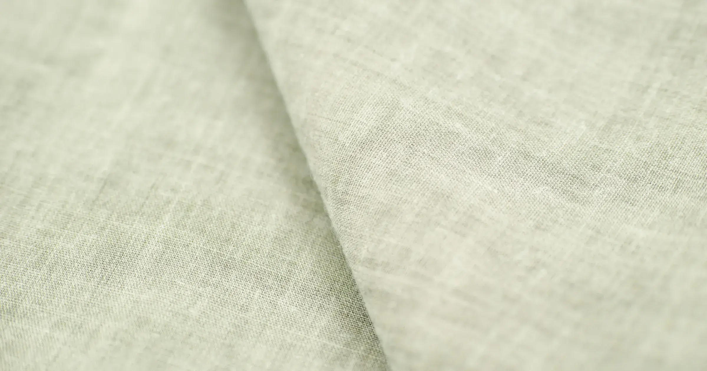 Close-up of pale linen shirting fabric with a single soft fold across the weave