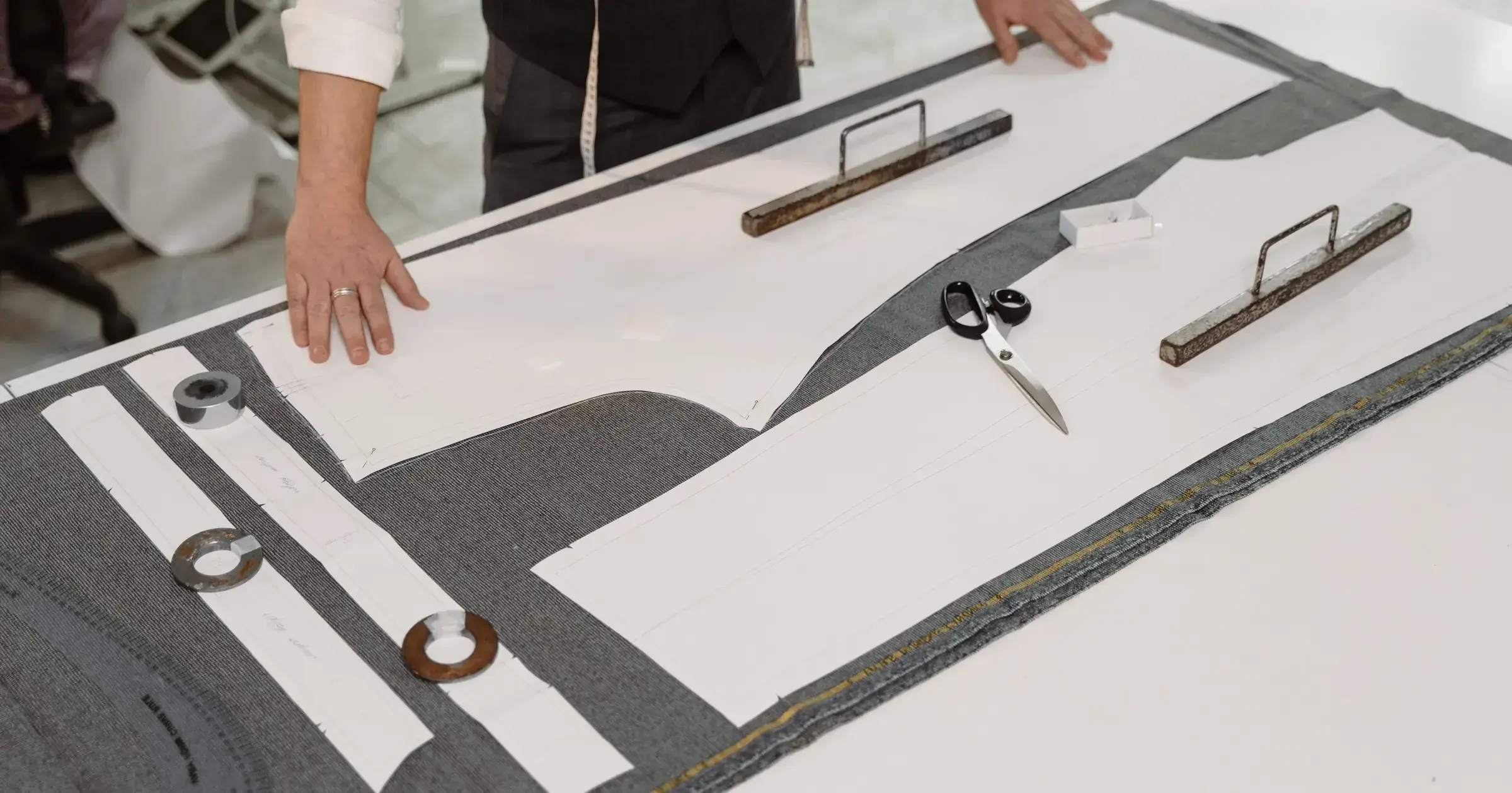 Tailors arranging production pattern pieces on fabric at a worktable
