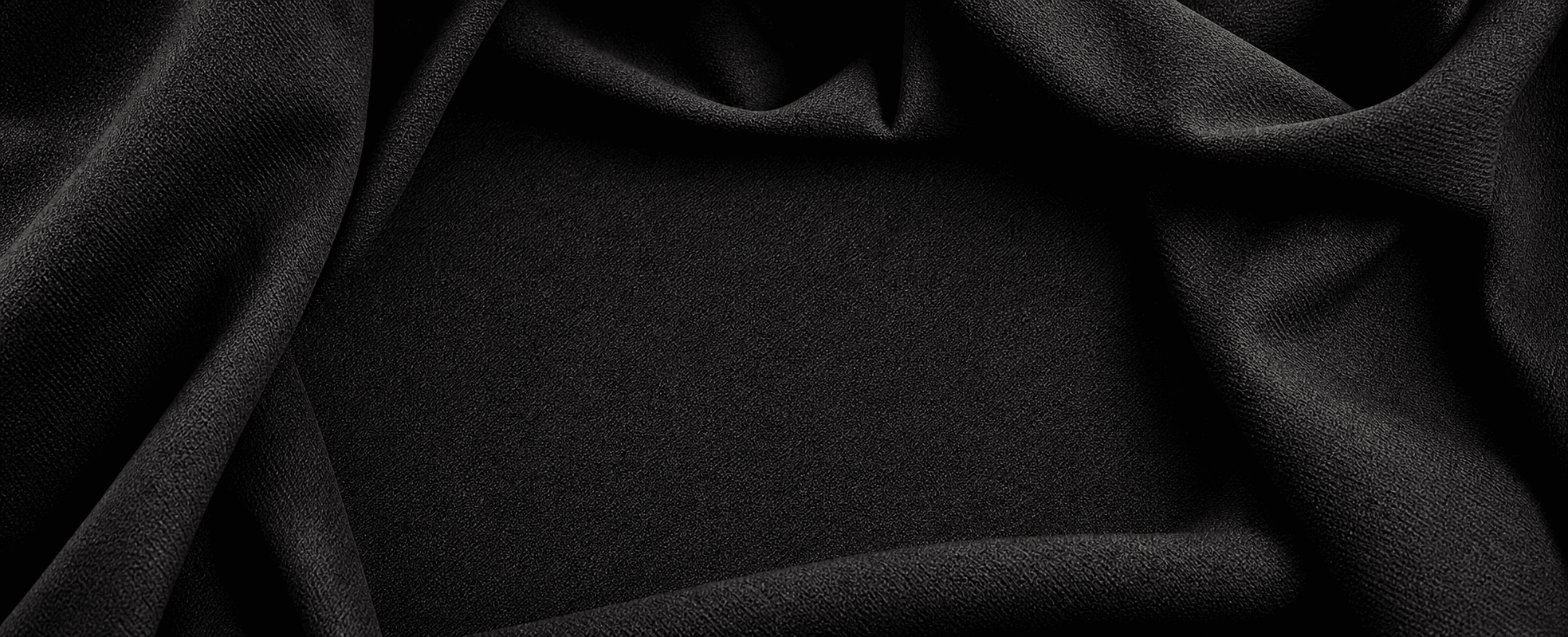 Dark woven fabric folded into a clean hero background for apparel sample development
