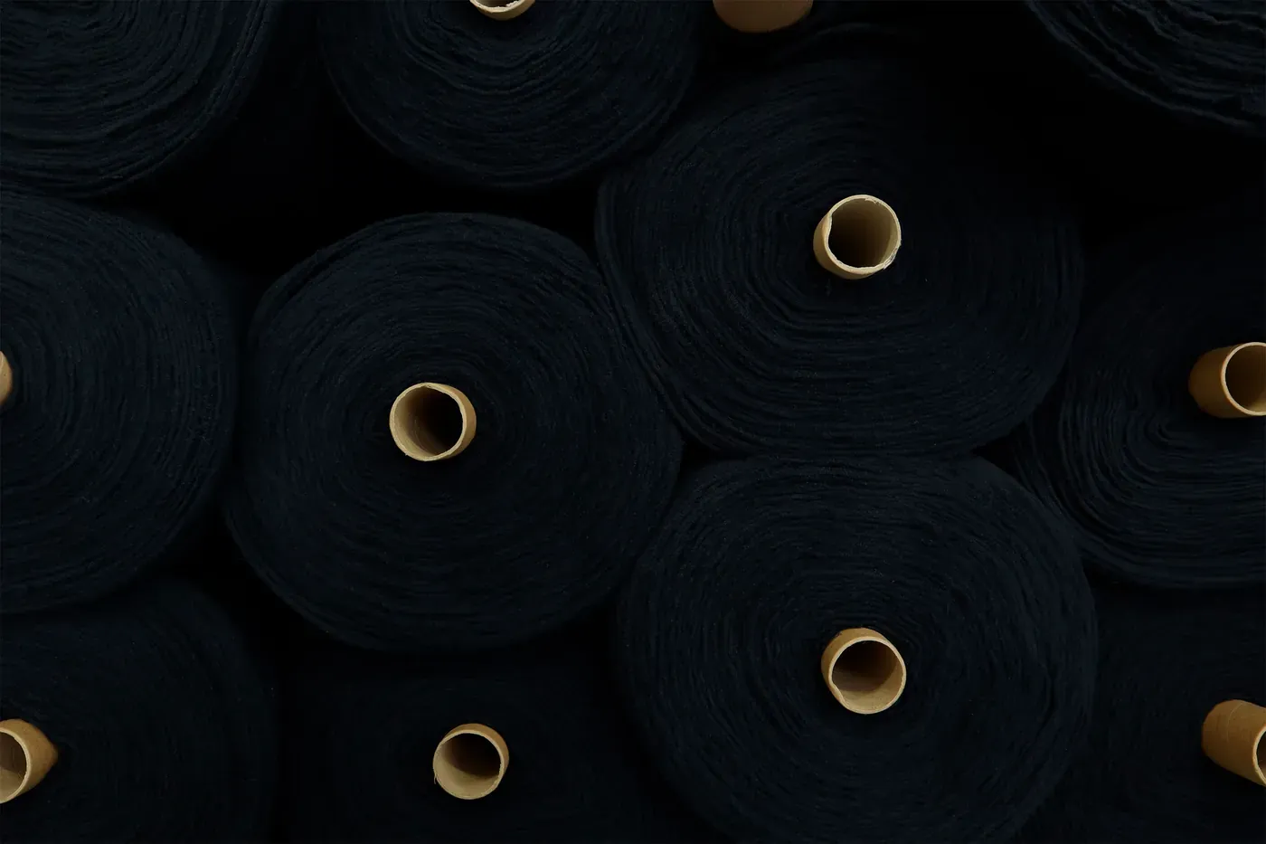 Rolls of dark navy fabric stacked on cardboard cores