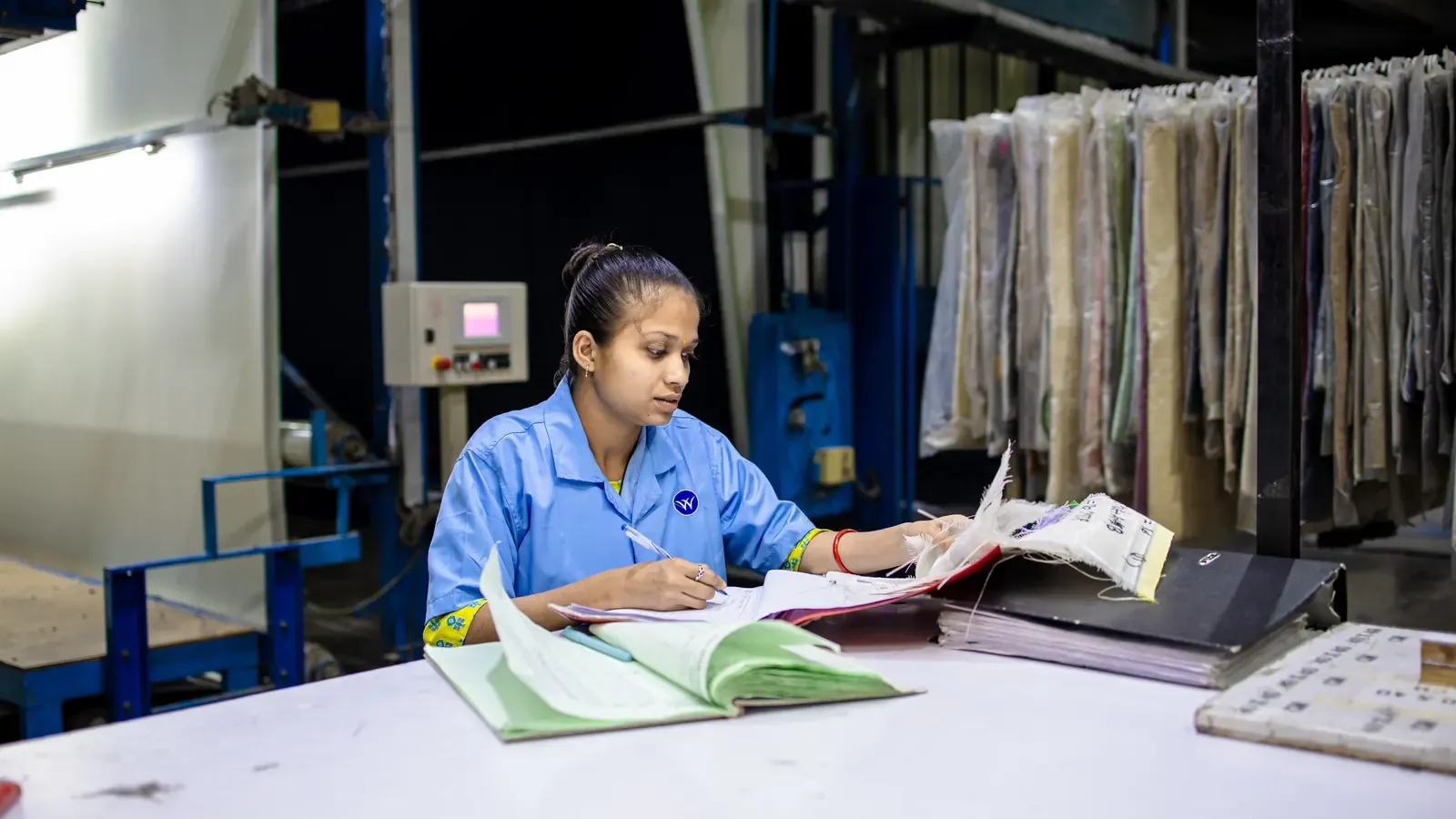 Textile production specialist reviewing documents at a factory workstation
