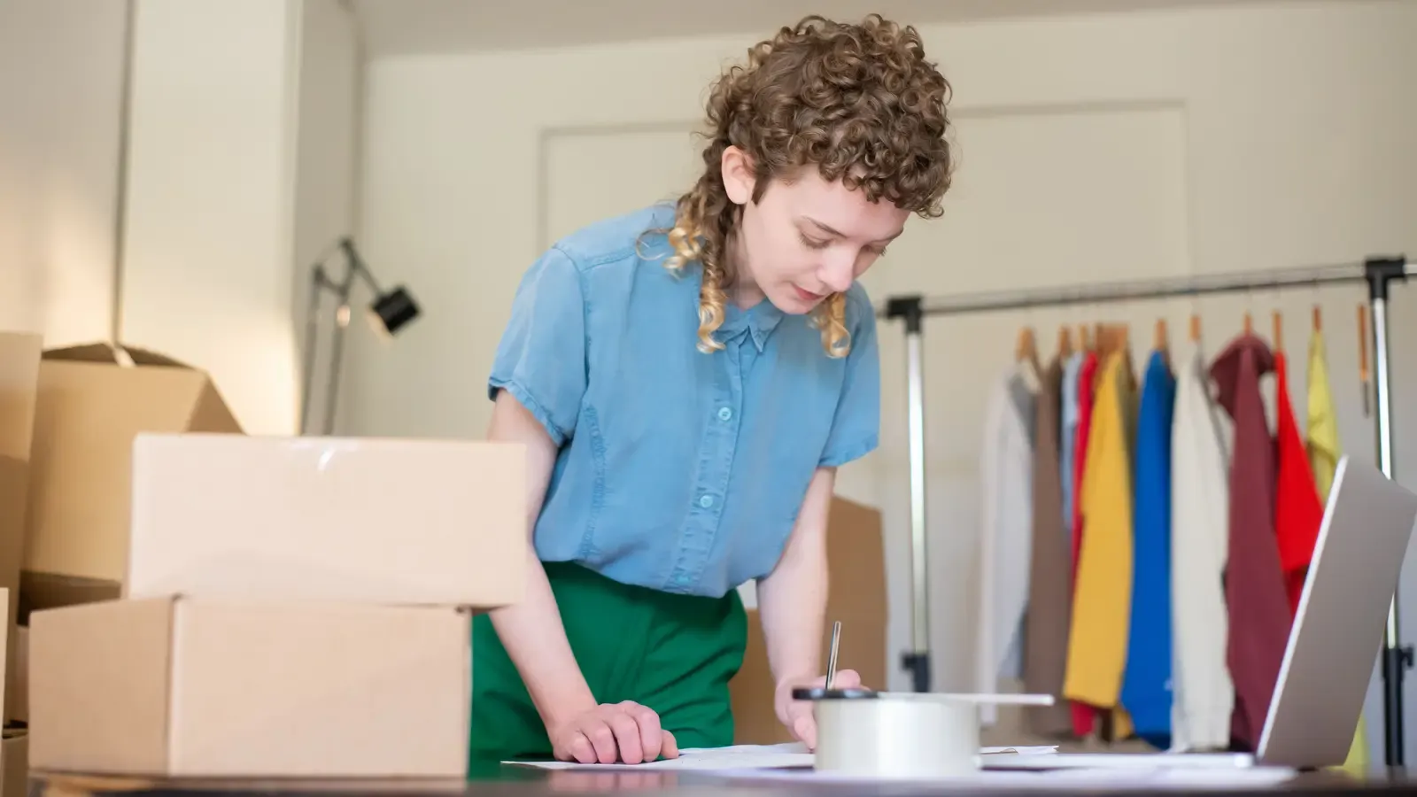 Apparel buyer reviewing order paperwork beside a clothing rack and boxes