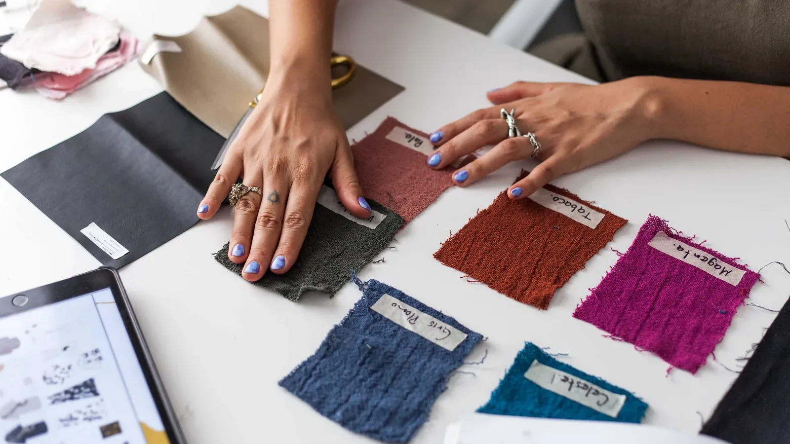 Hands arranging labeled fabric swatches with handwritten color names