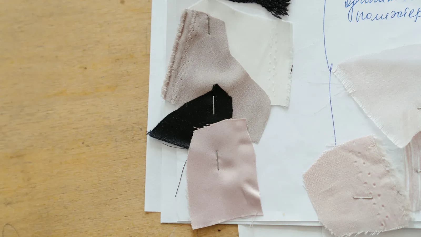 Fabric swatches pinned to an annotated worksheet on a wooden table