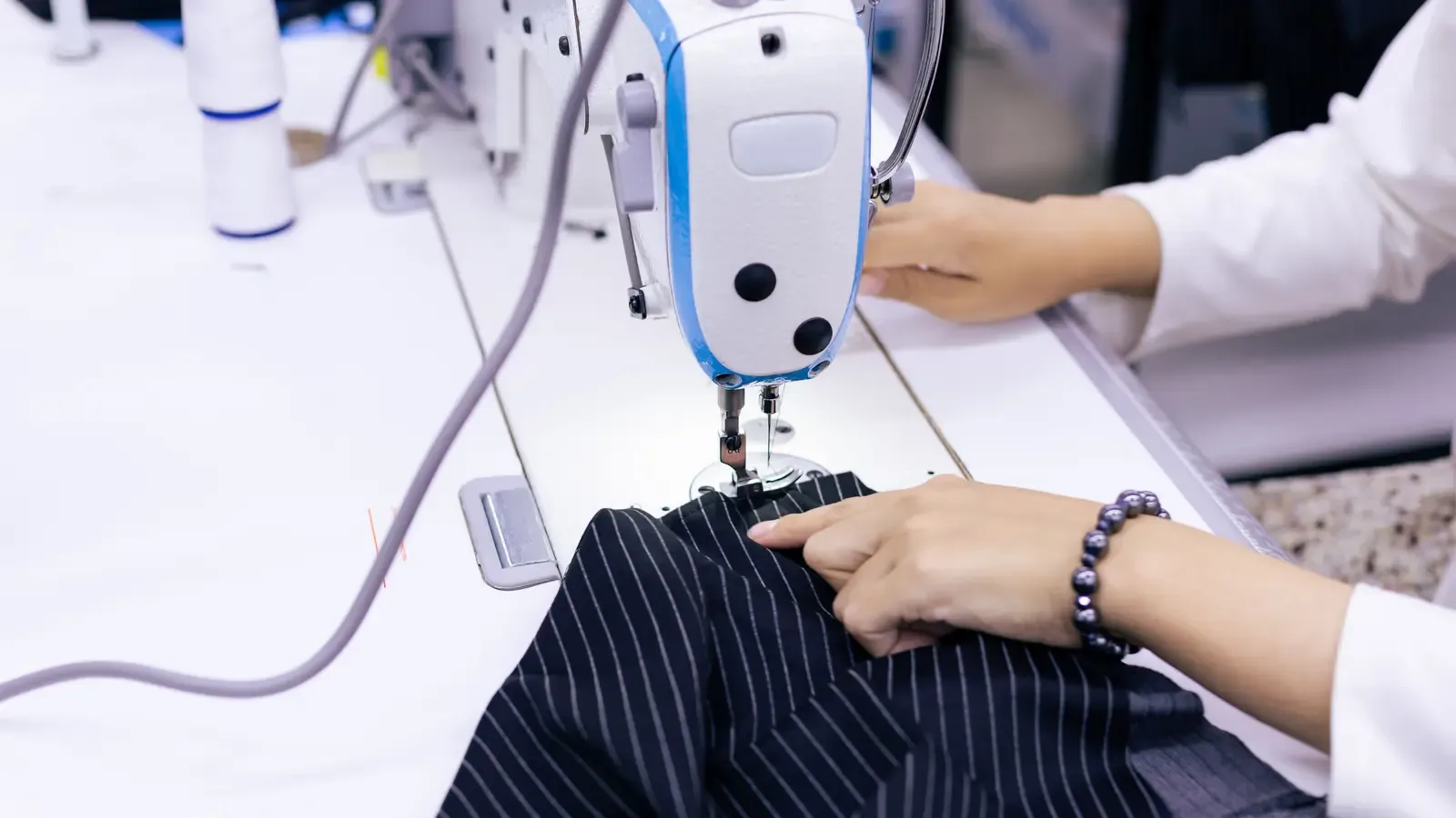 Operator sewing a striped collared garment on an industrial machine