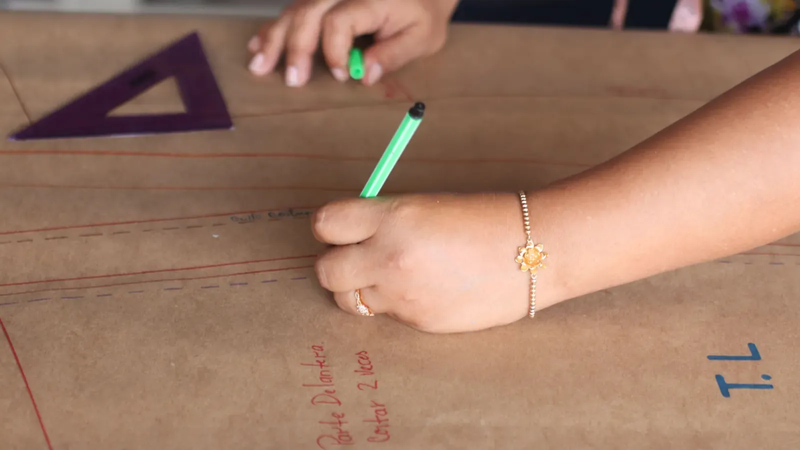 Pattern maker drawing full-scale lines and construction marks on brown pattern paper