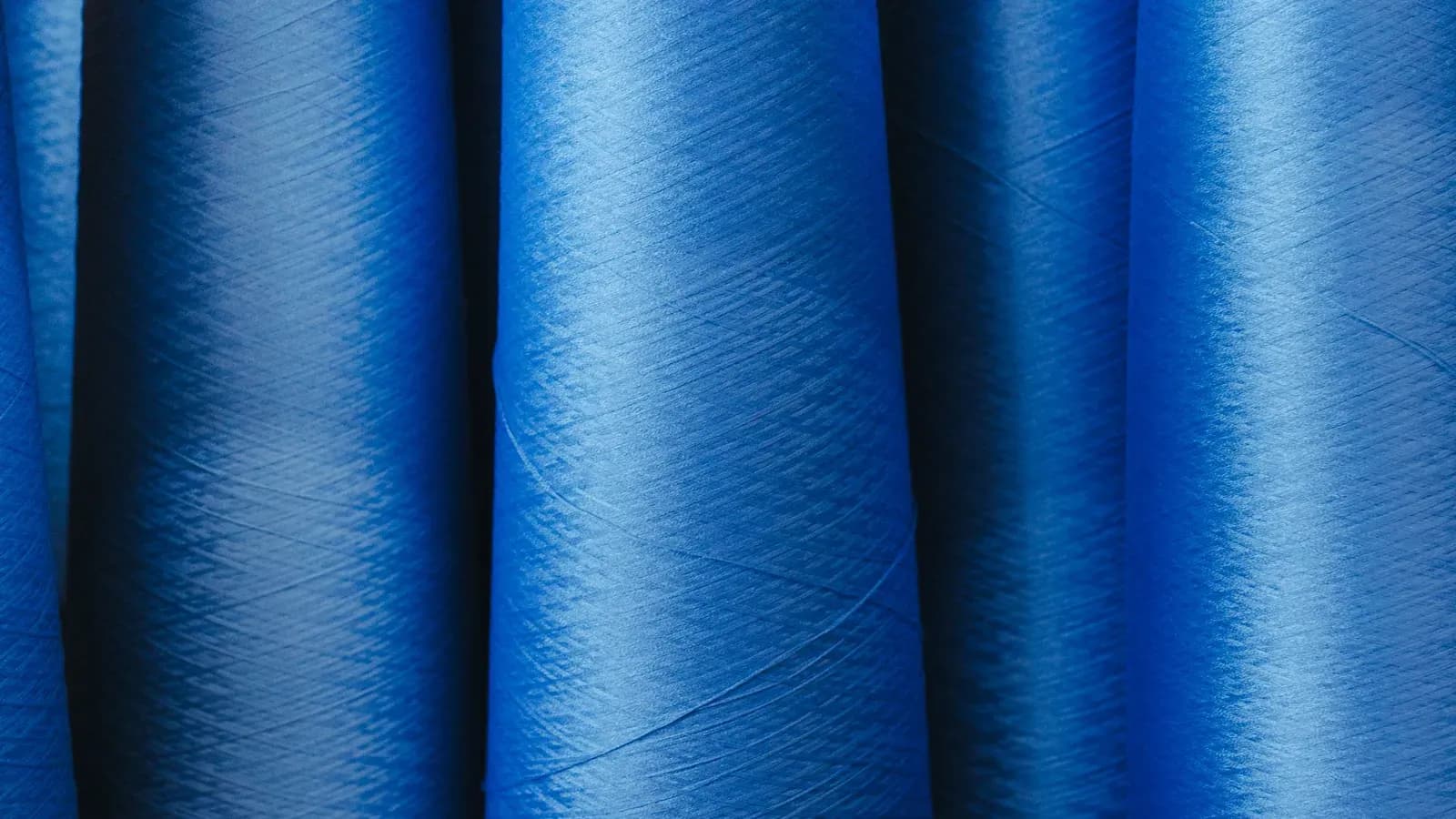 Rows of blue spun yarn packages seen in close-up