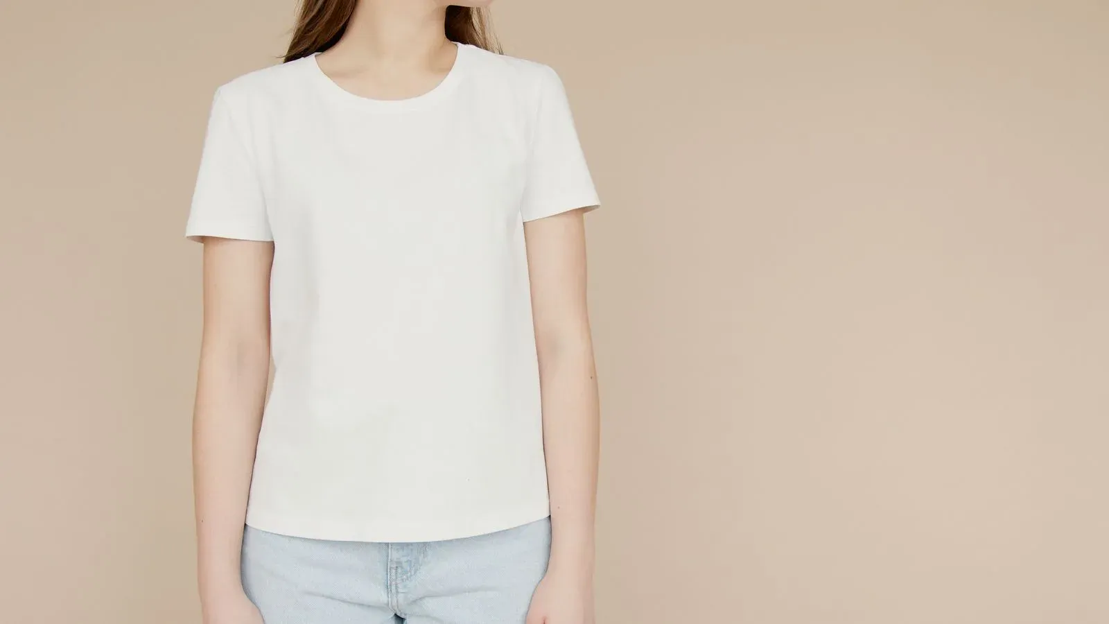 Model wearing a plain white crew-neck T-shirt against a beige background
