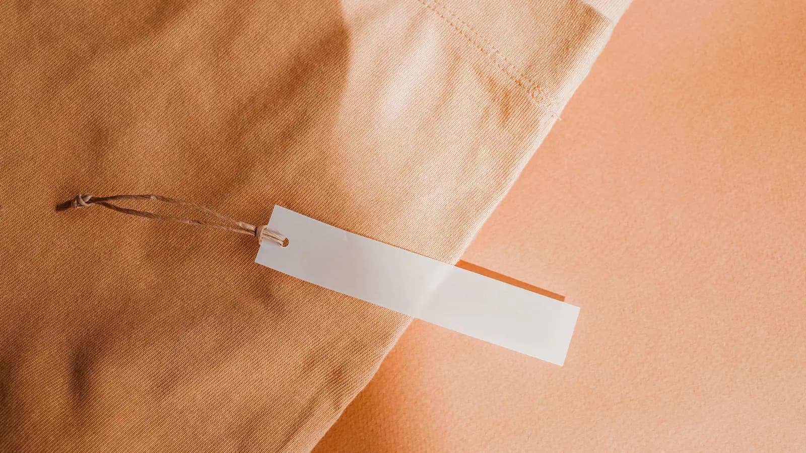 A blank white hang tag attached to plain cotton jersey fabric