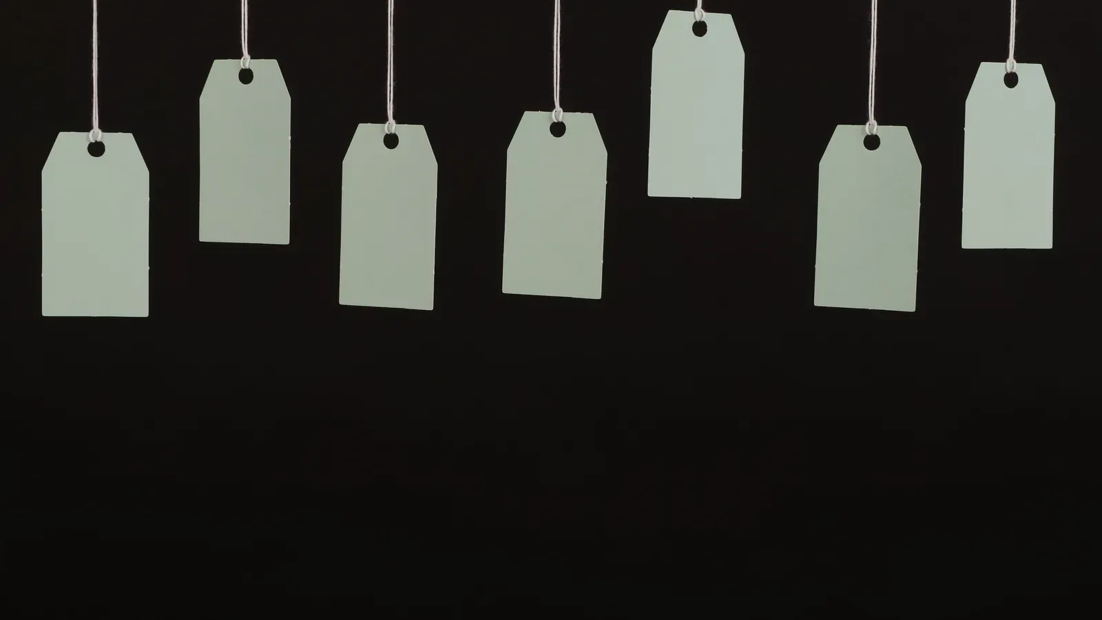 Blank hang tags hanging on strings against a dark background