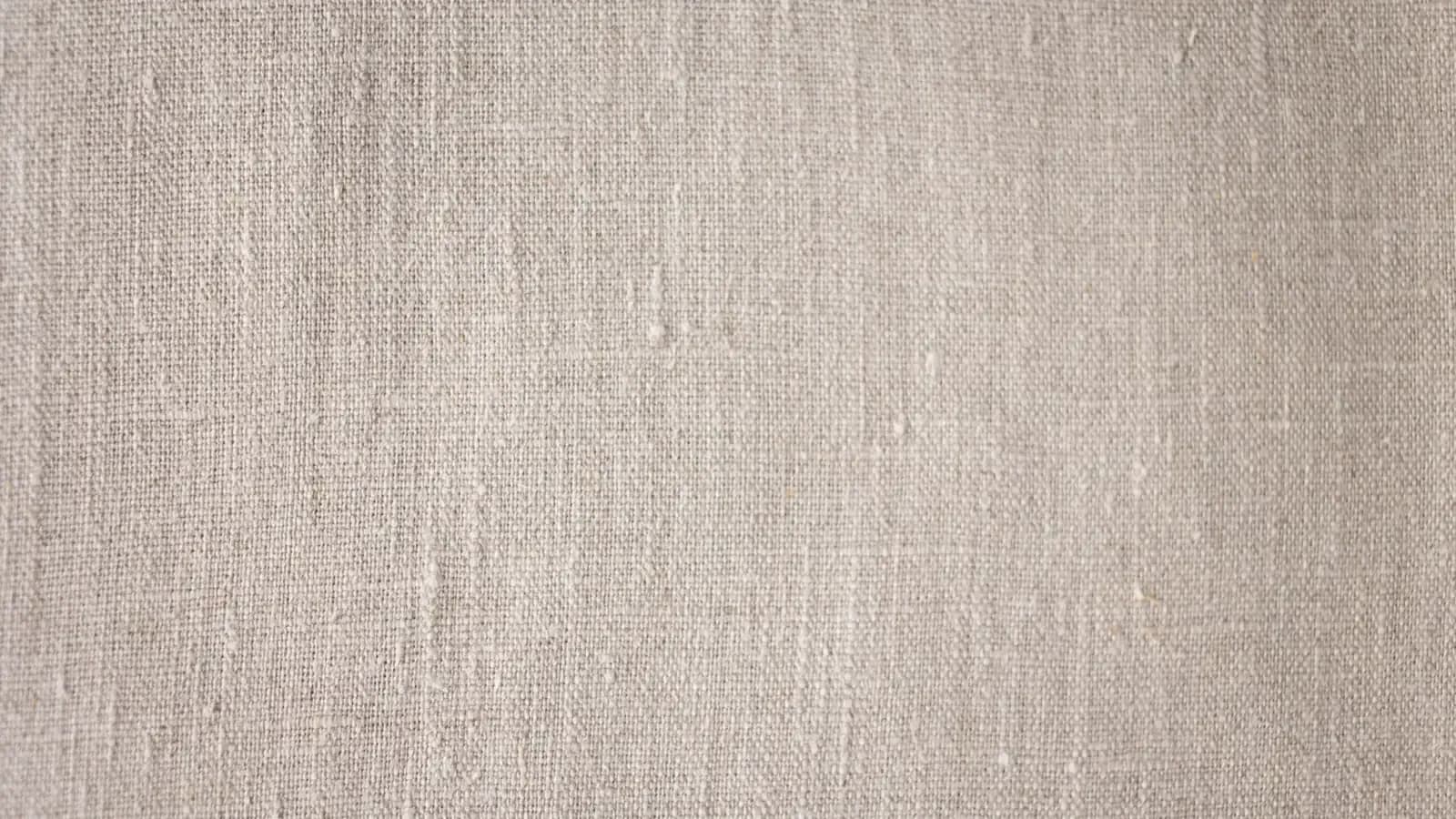 Close-up of natural undyed linen showing visible slub and irregular yarn in the weave