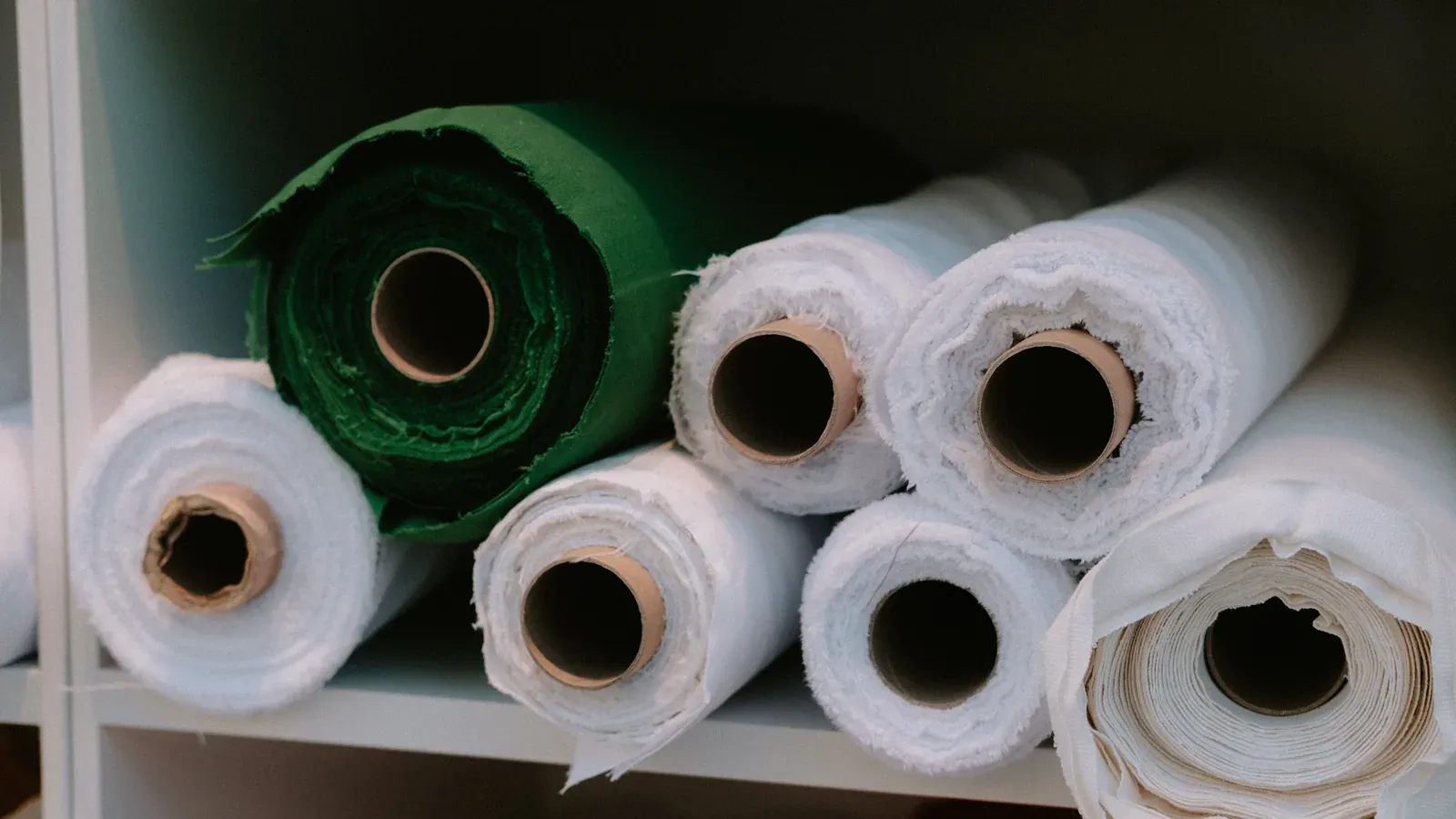 Rolls of white and green fabric stored on a warehouse shelf