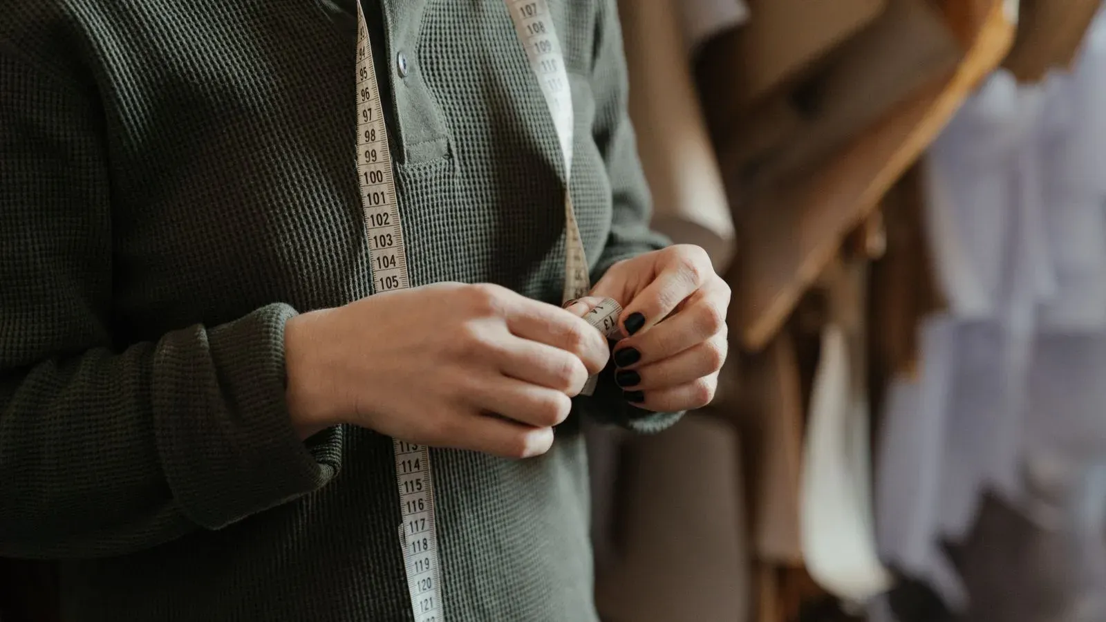 Garment developer holding a measuring tape in a sewing workspace