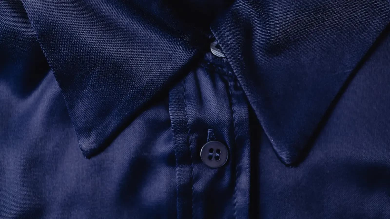 Close-up of a navy collared shirt showing fabric, collar and buttons