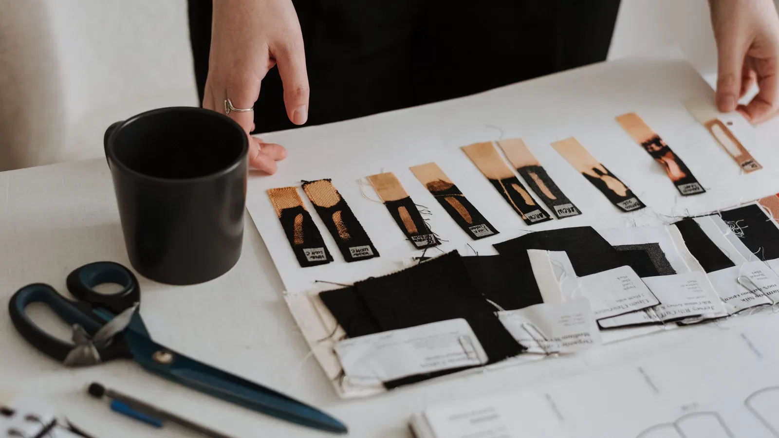 Garment labels, fabric pieces and construction references arranged on a design table