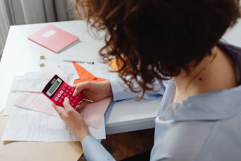 A person calculating a budget with a calculator and documents