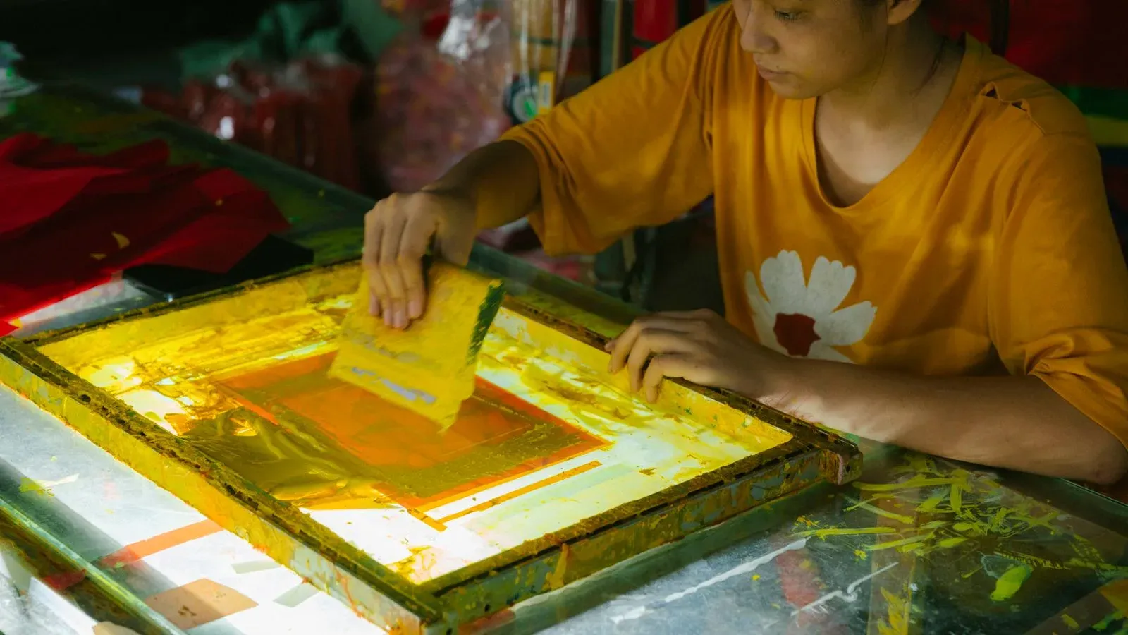 Screen-printing operator pulling ink across a print screen