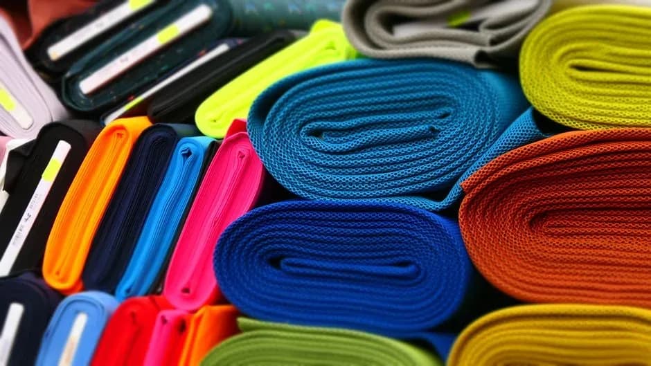 Rolls of colorful knitted fabric stacked in a textile shop