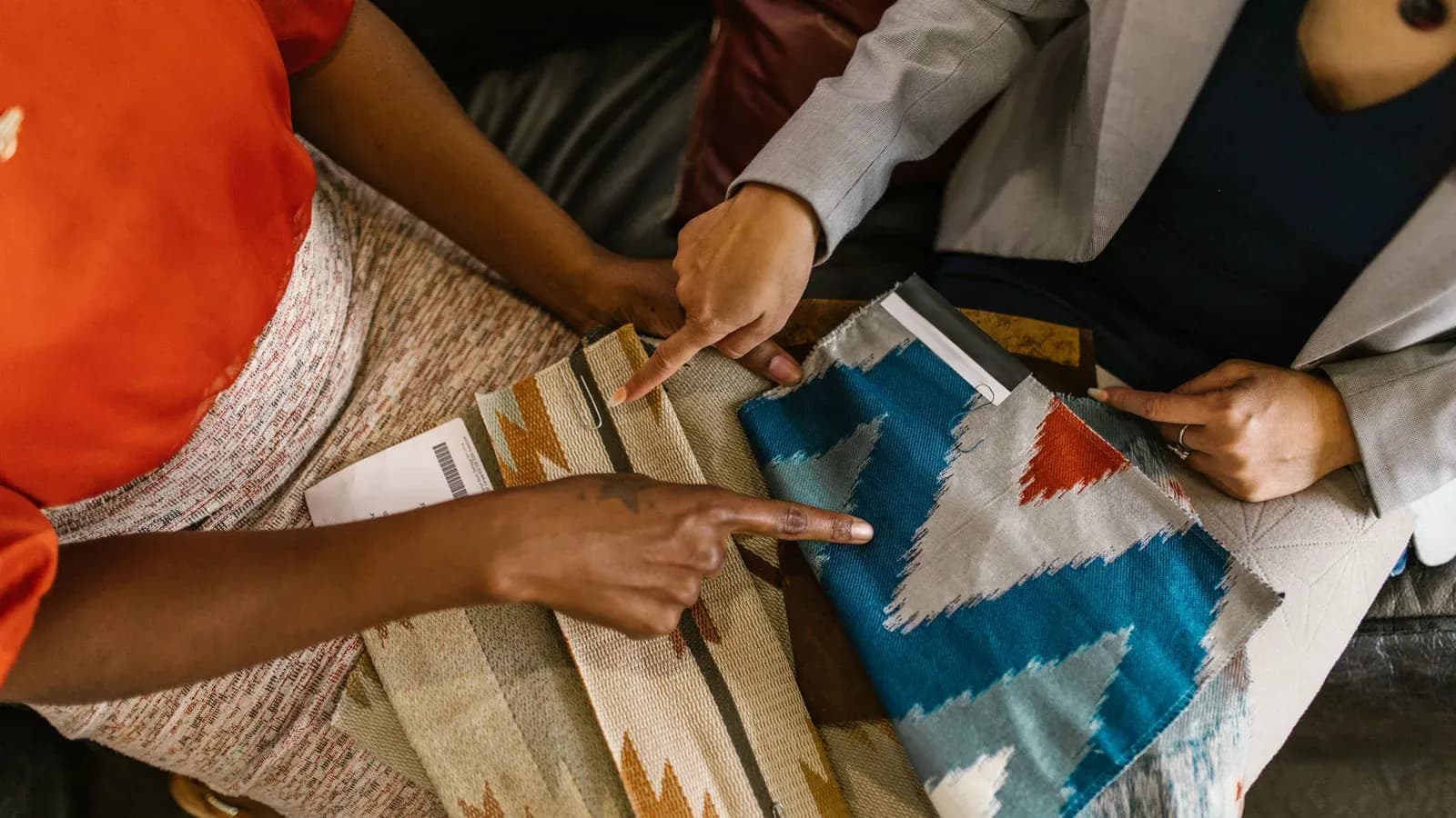 Two people comparing woven fabric samples with patterned swatches
