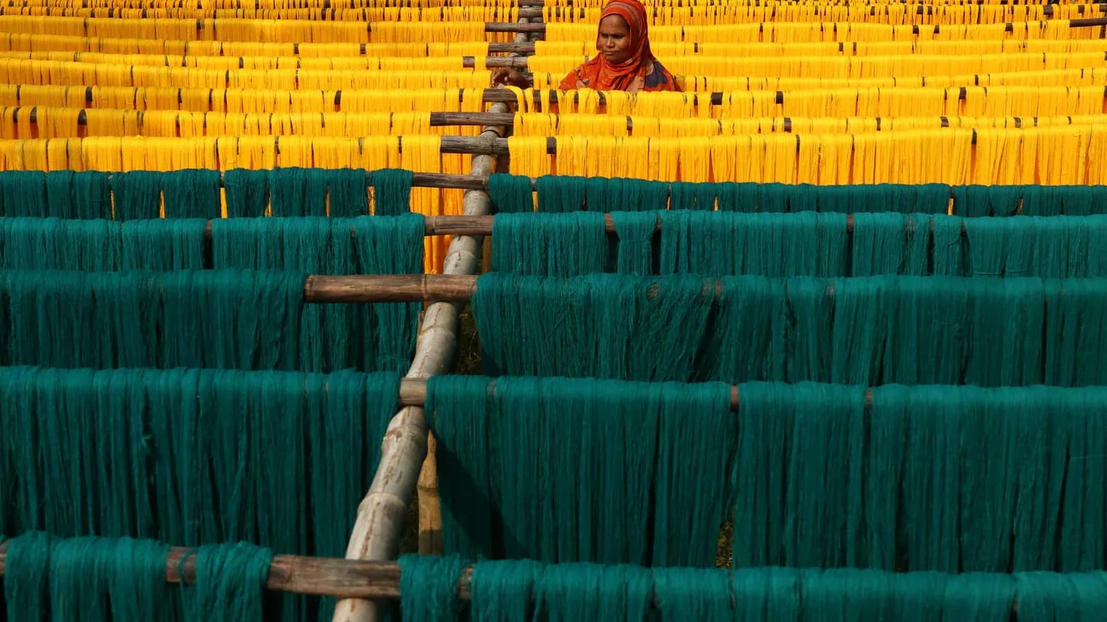 Rows of freshly dyed yellow and teal fabric hanging to dry