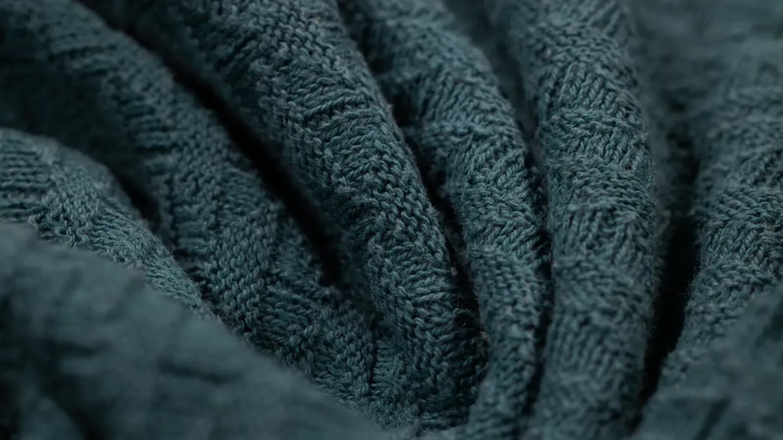 Macro view of a dark knitted fabric showing individual loops and stitch structure