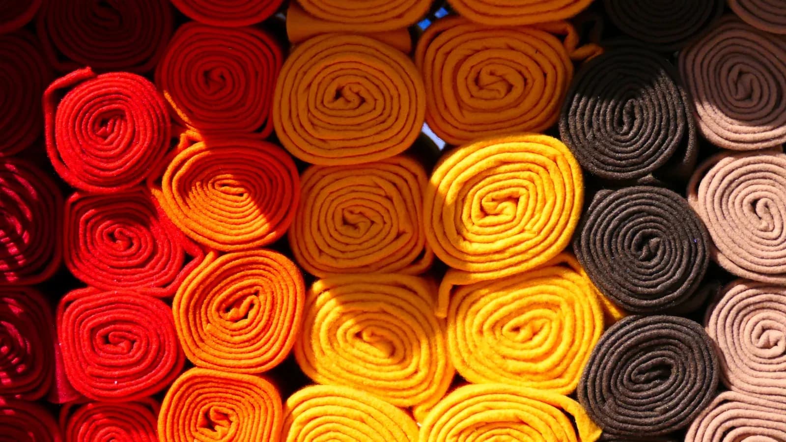 Rolled fabric bolts in warm colors displayed at a textile market