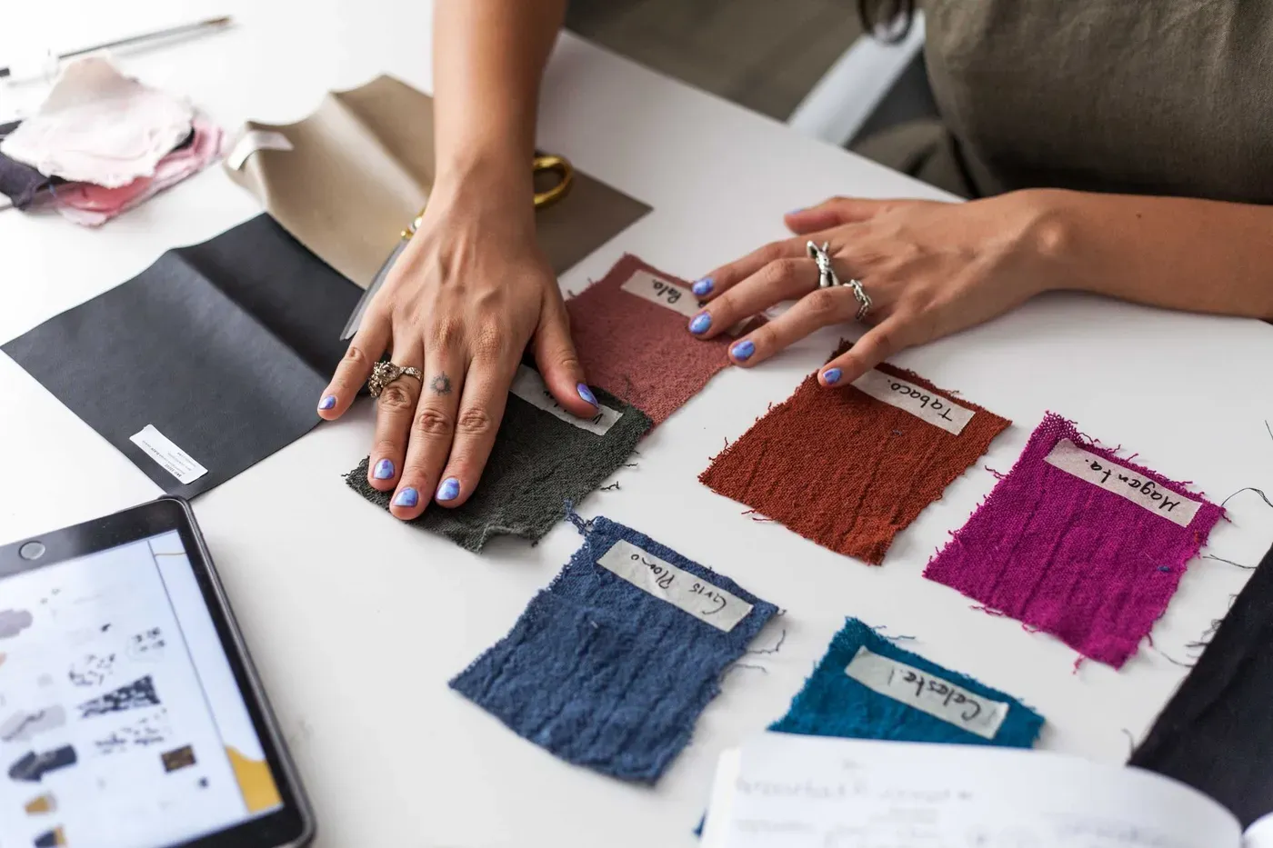 Hands arranging labeled fabric swatches on a worktable
