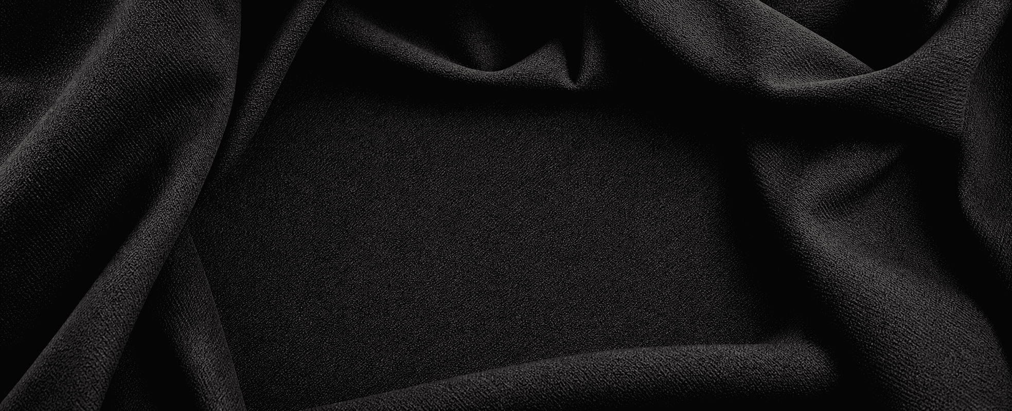 Dark woven fabric folded into a clean hero background for apparel sample development