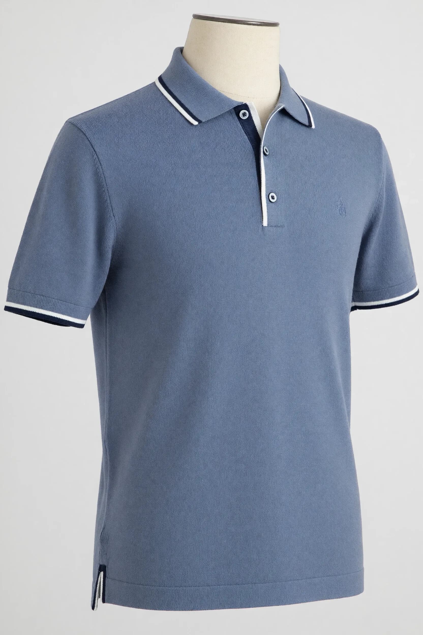 Dusty blue double-tipped short-sleeve knit polo displayed on a mannequin for private-label contrast-color development