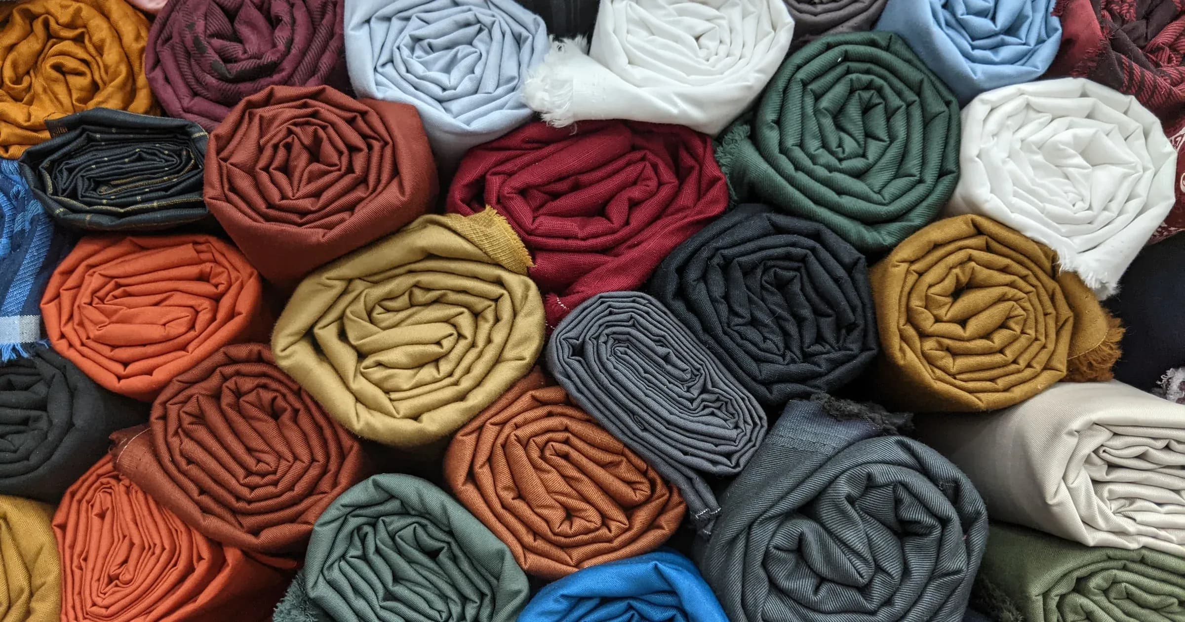 Rolled fabric bolts in solid earth-tone colors stacked for selection
