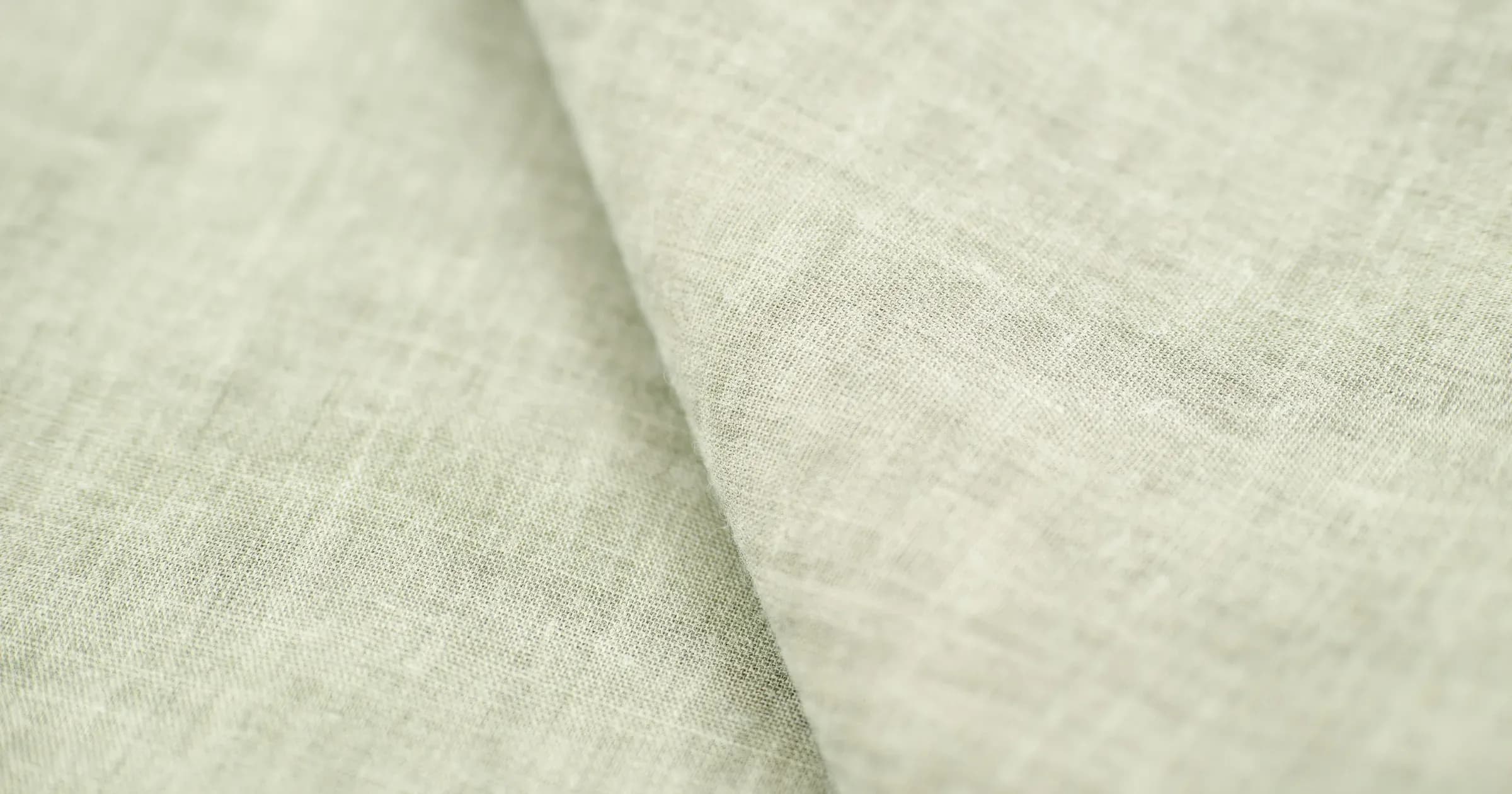 Close-up of pale linen shirting fabric with a single soft fold across the weave