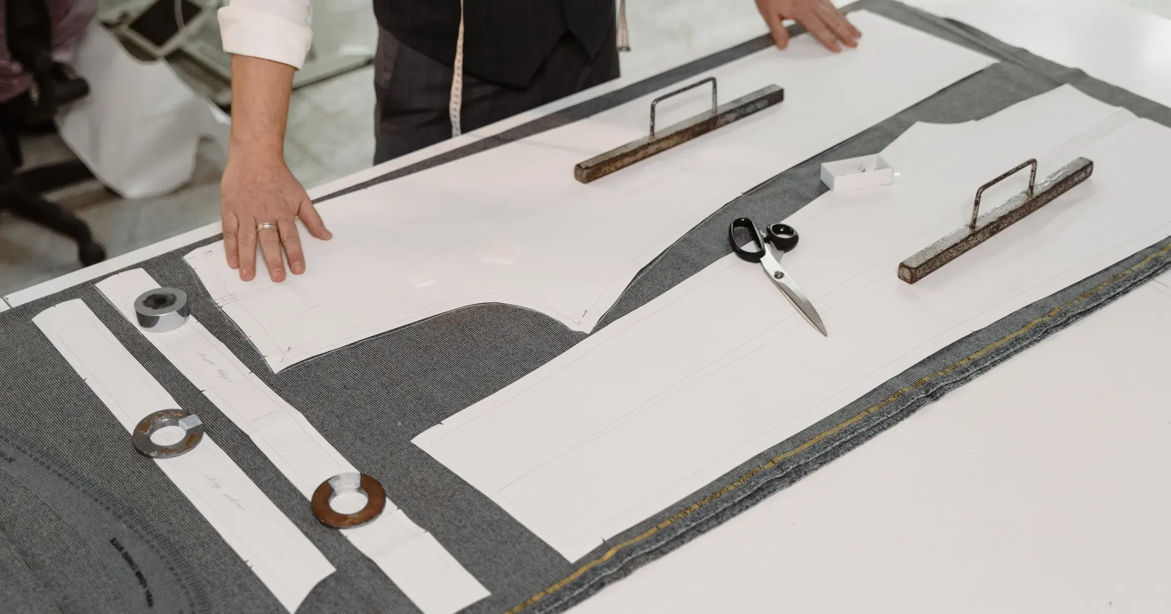 Tailors arranging production pattern pieces on fabric at a worktable
