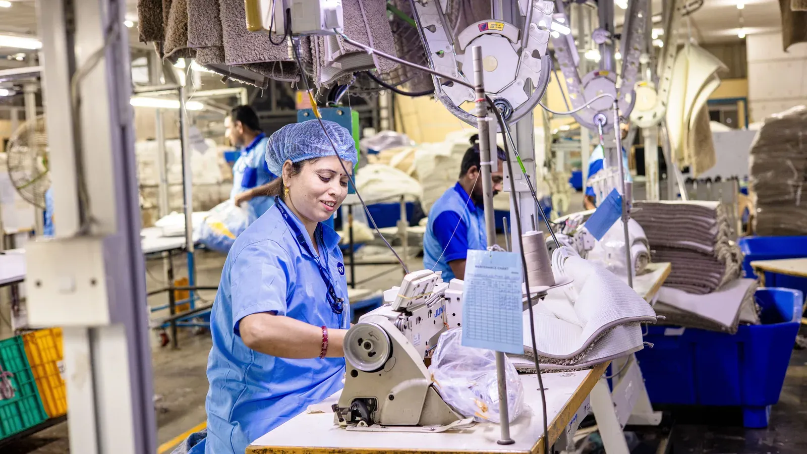Garment worker operating an overlock machine on a production line