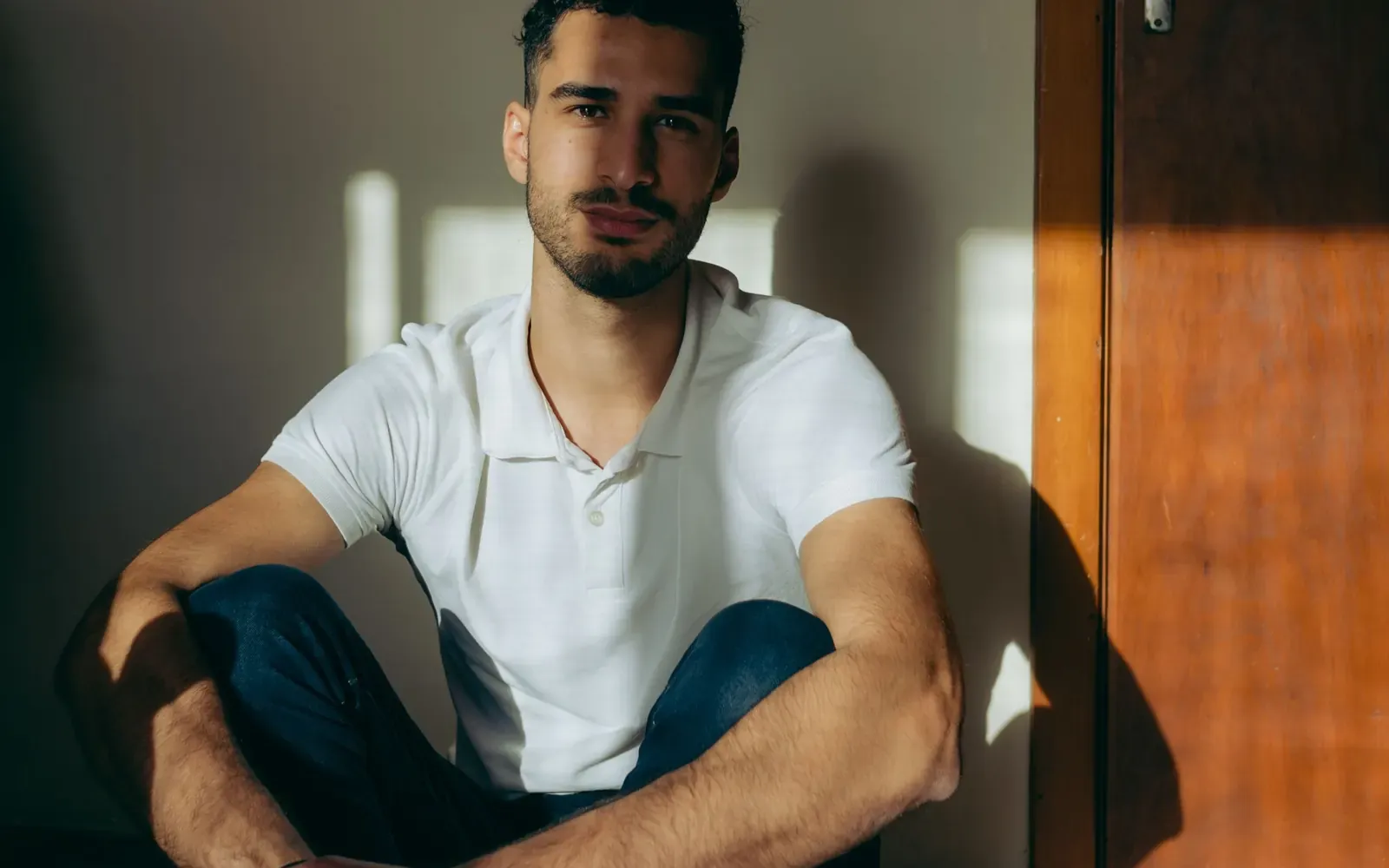 Man wearing an unbranded white polo shirt in natural light