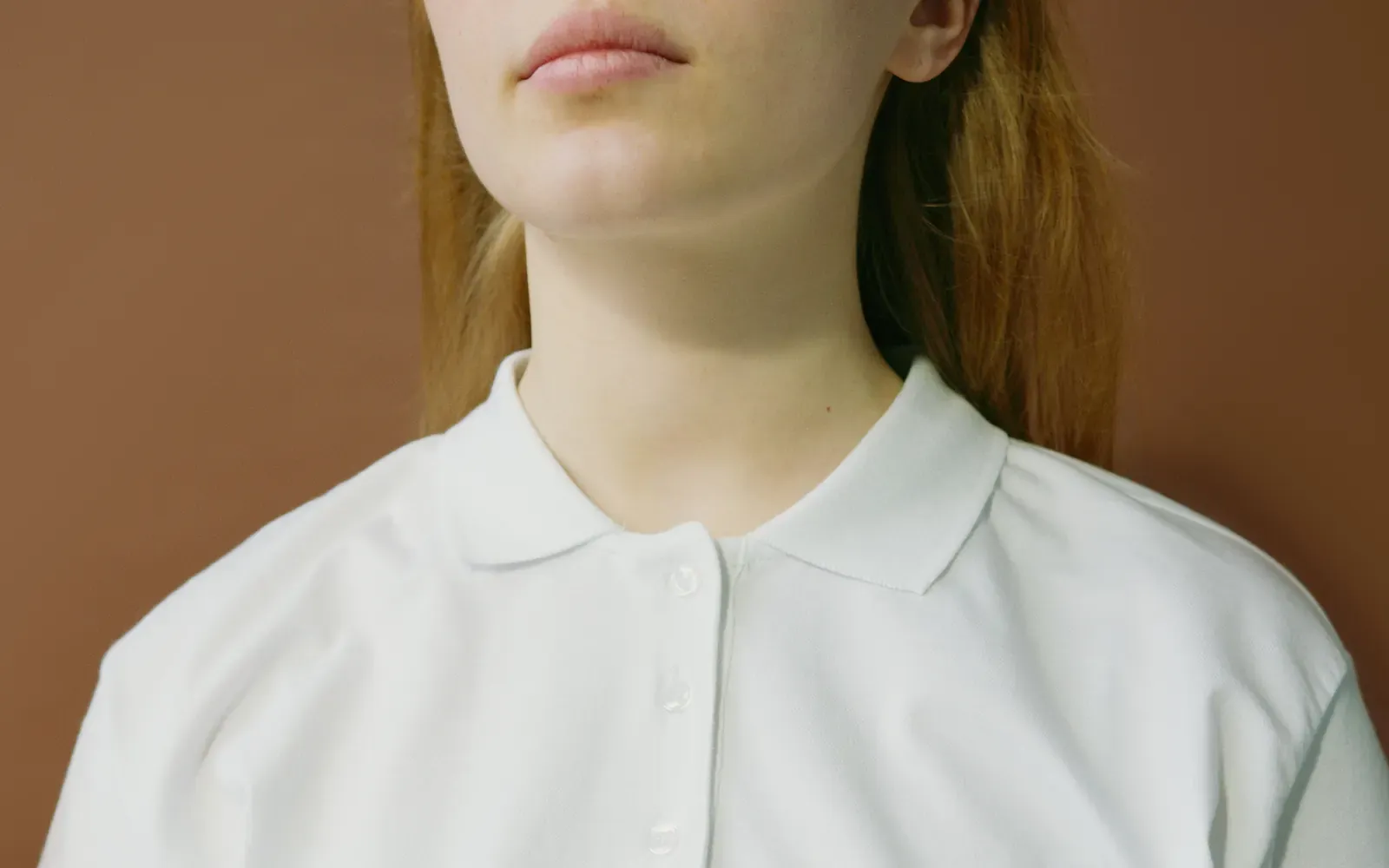 Close-up of an unbranded white polo shirt with a flat collar and three-button placket